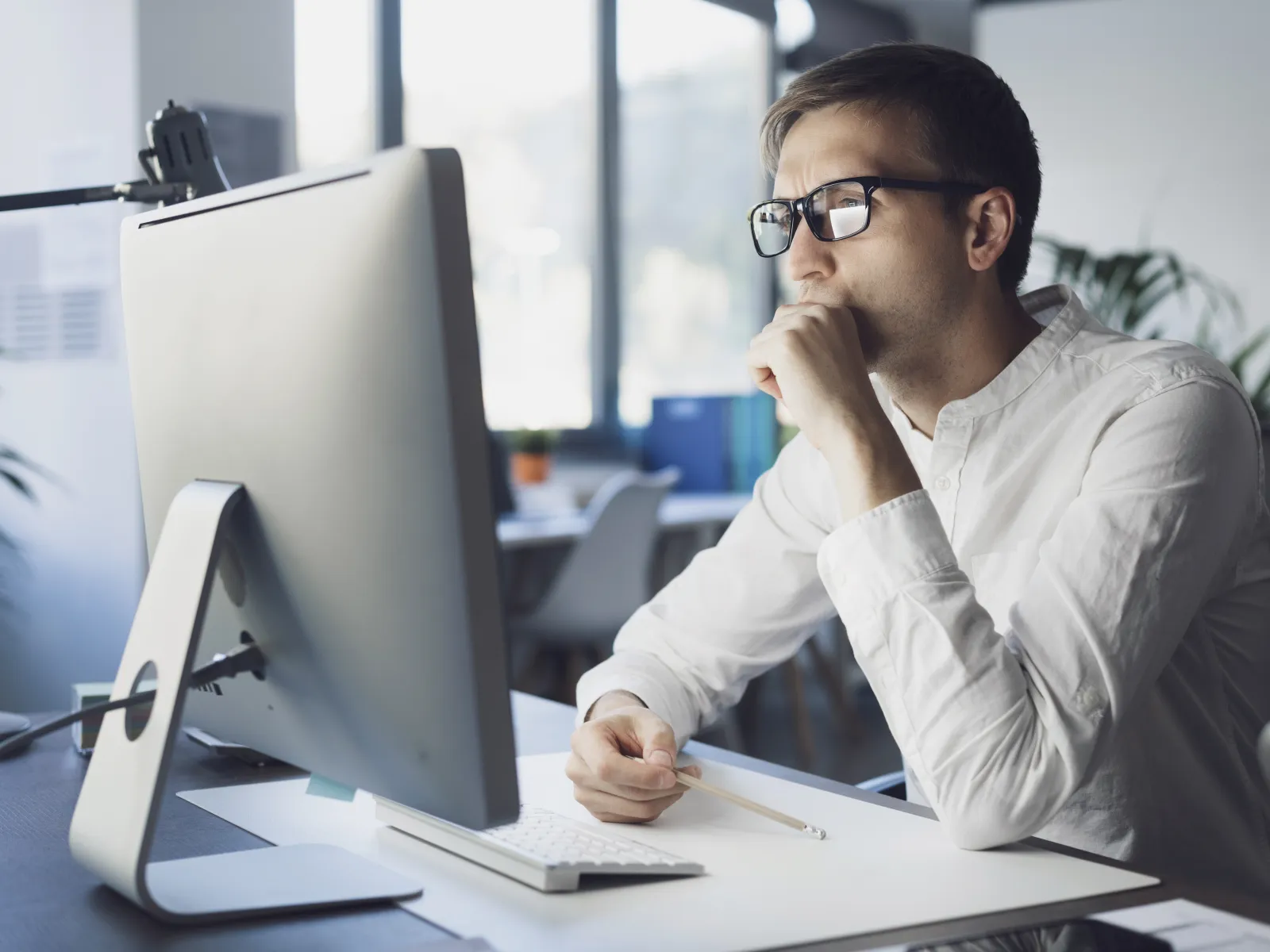 a man sitting at a desk with his hand on his chin