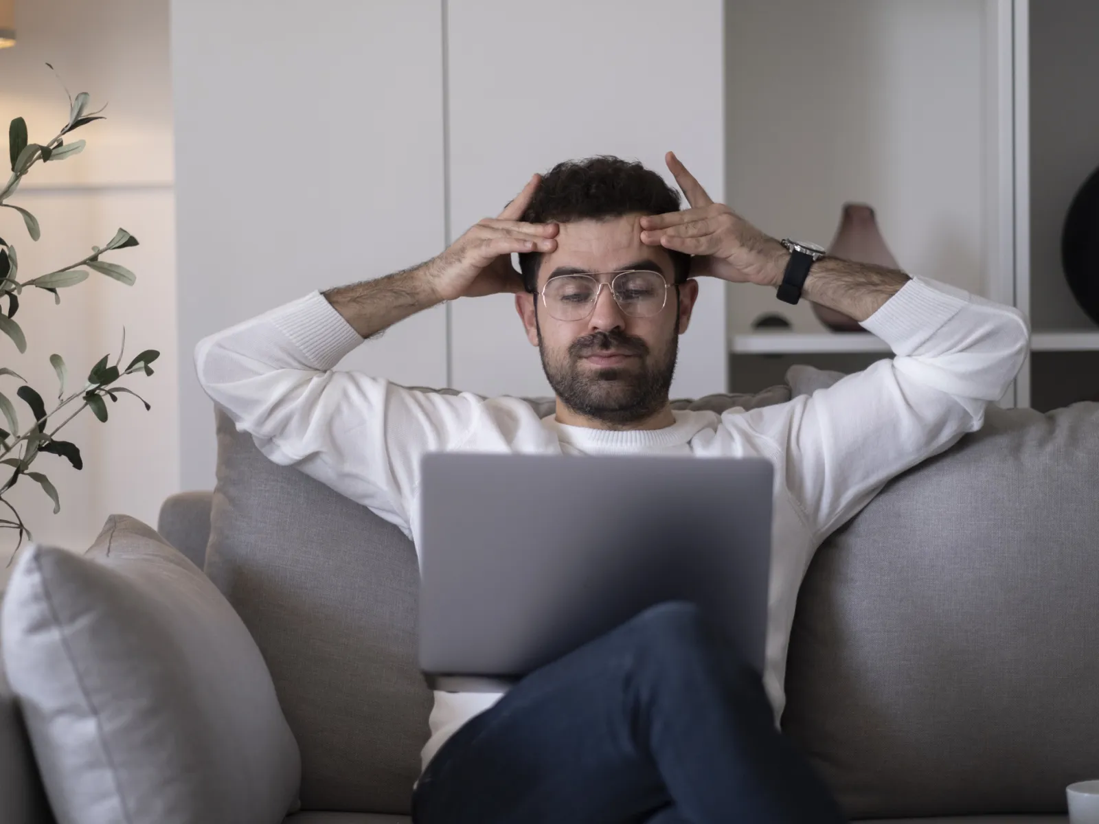 a man sitting on a couch with his hands on his head