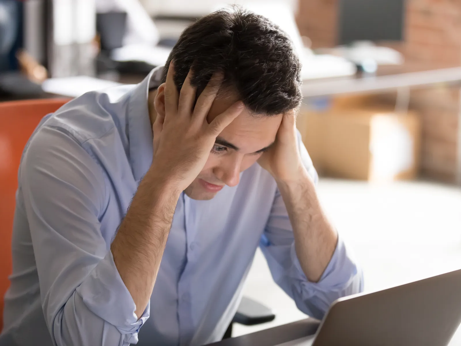 a person with the head in the hands looking at a laptop