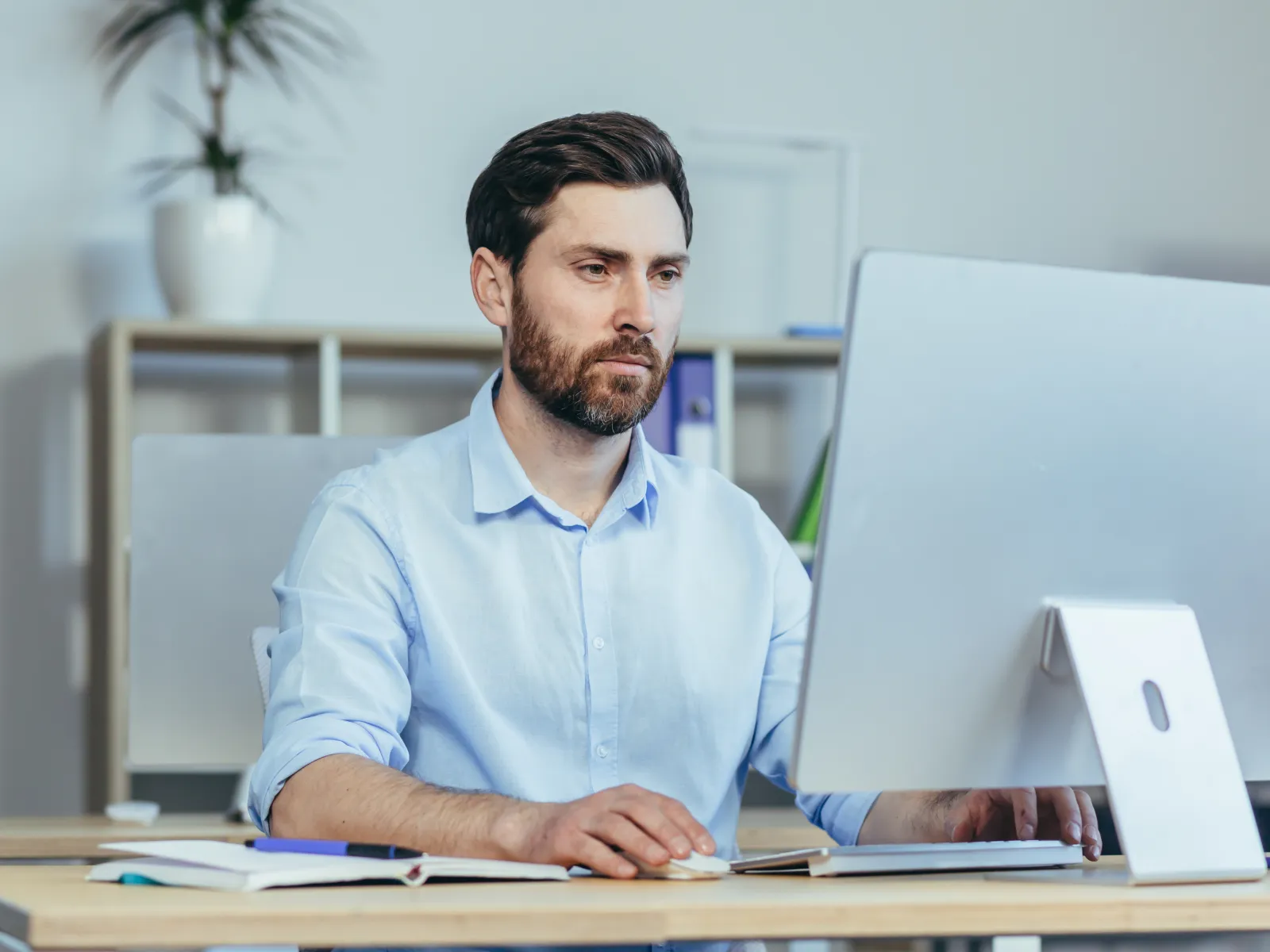 Concentrated man working on a computer in a bright, modern office space.