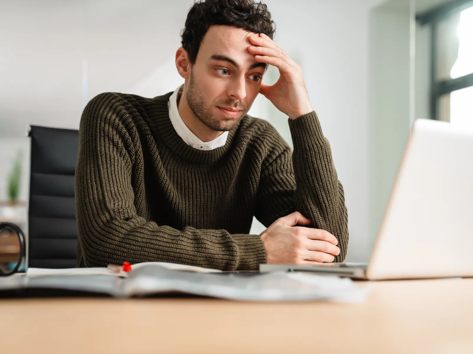 a man sitting at a desk with his hand on his head