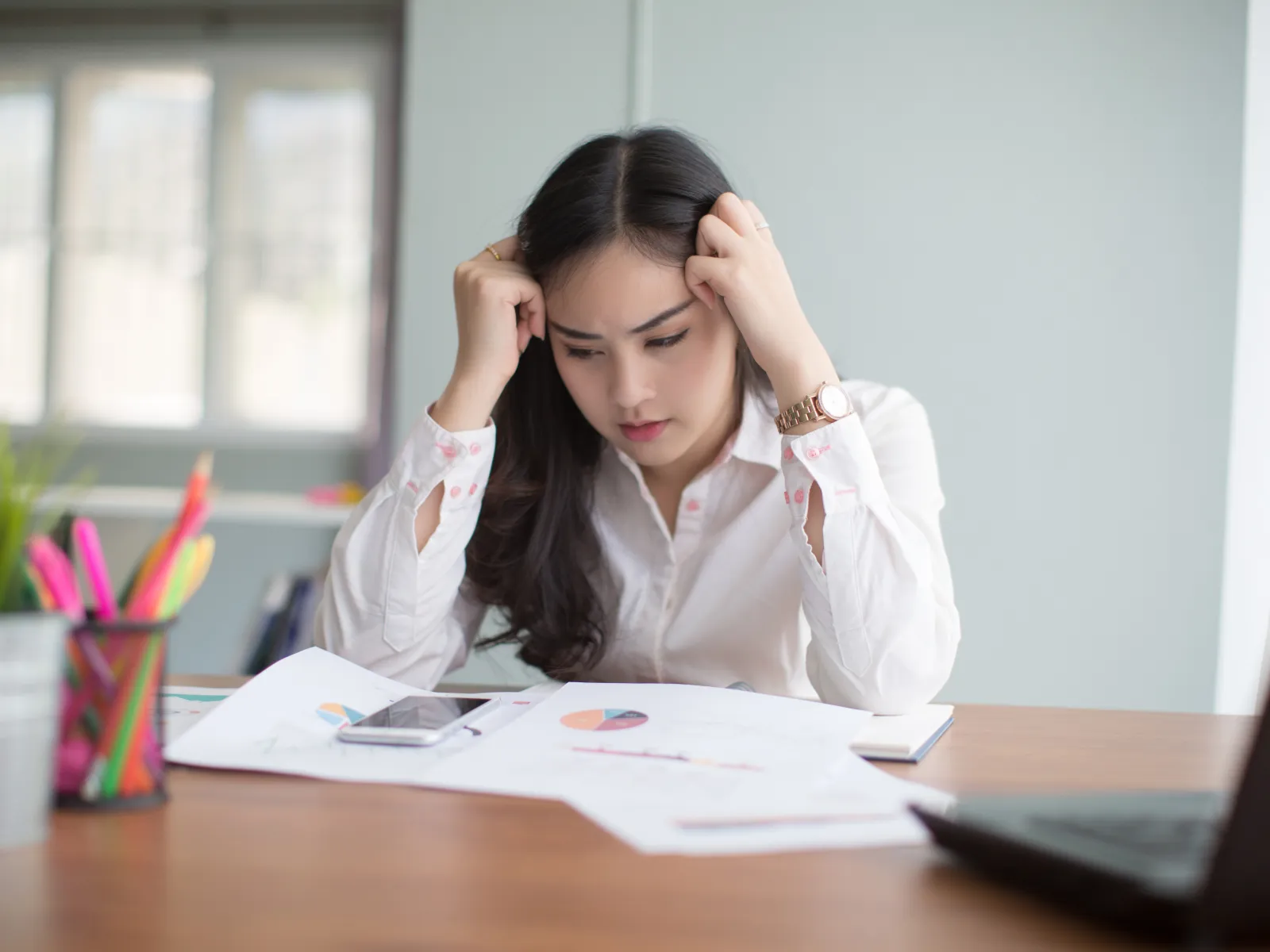 a woman sitting at a desk with her head in her hands