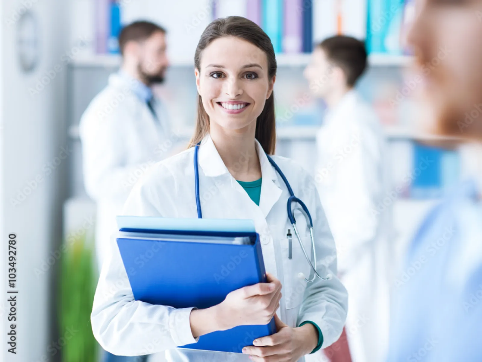 Smiling female doctor holding a blue folder in a bright medical office.