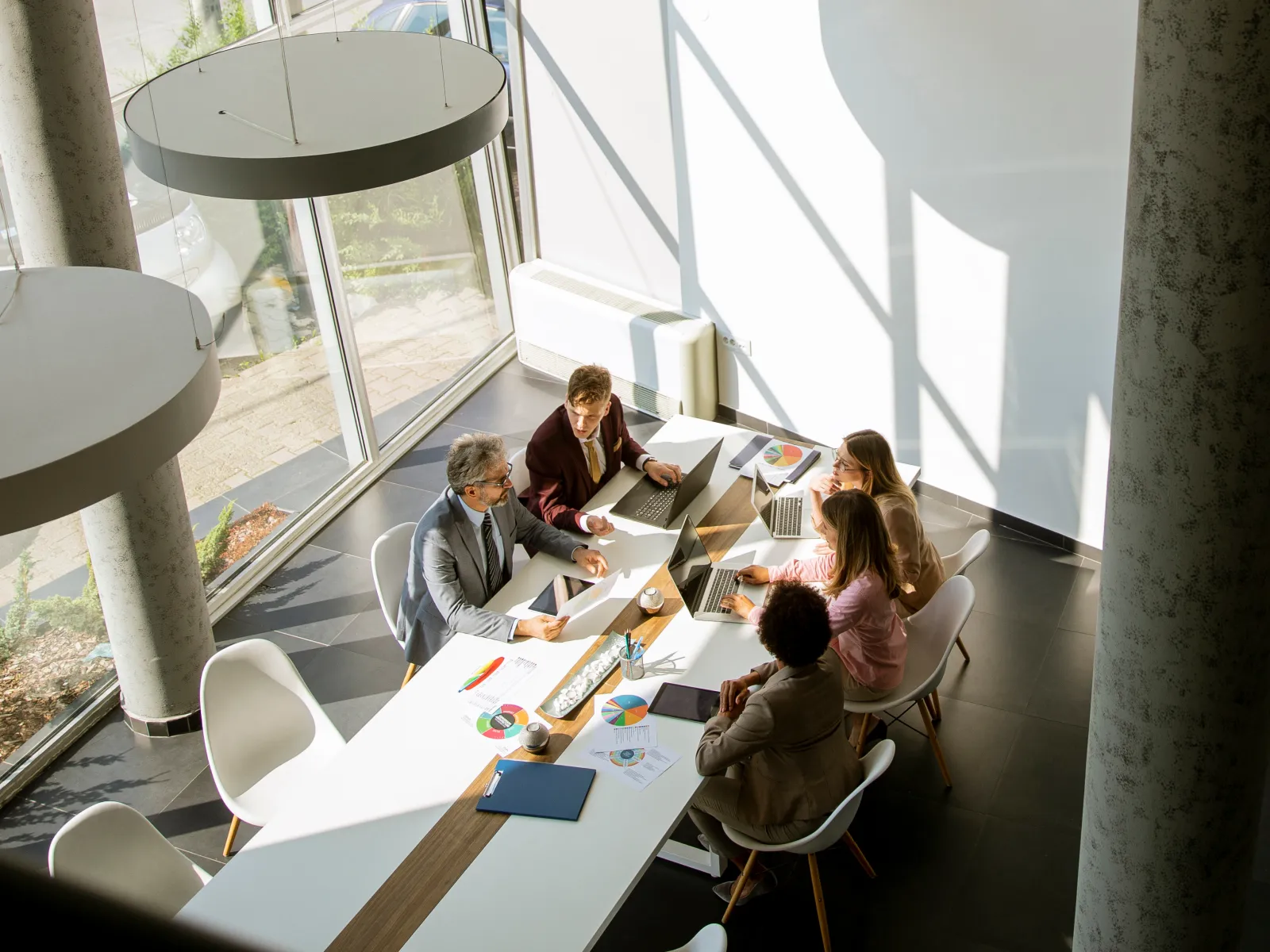 Business team collaborating in a modern office setting with large windows and natural light.