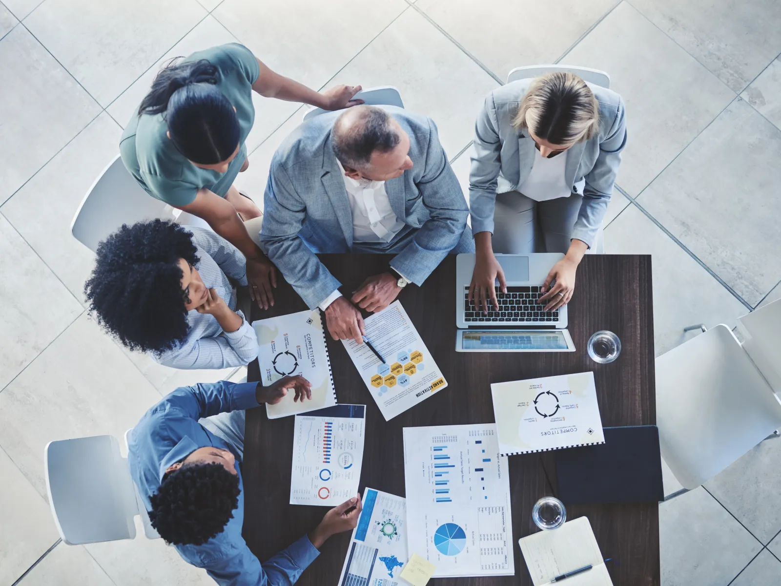 Top view of diverse business team discussing charts and data on a table with laptop in a meeting.