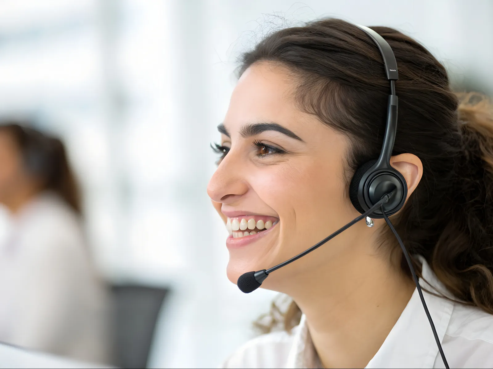 Smiling customer service representative wearing a headset in a bright office environment