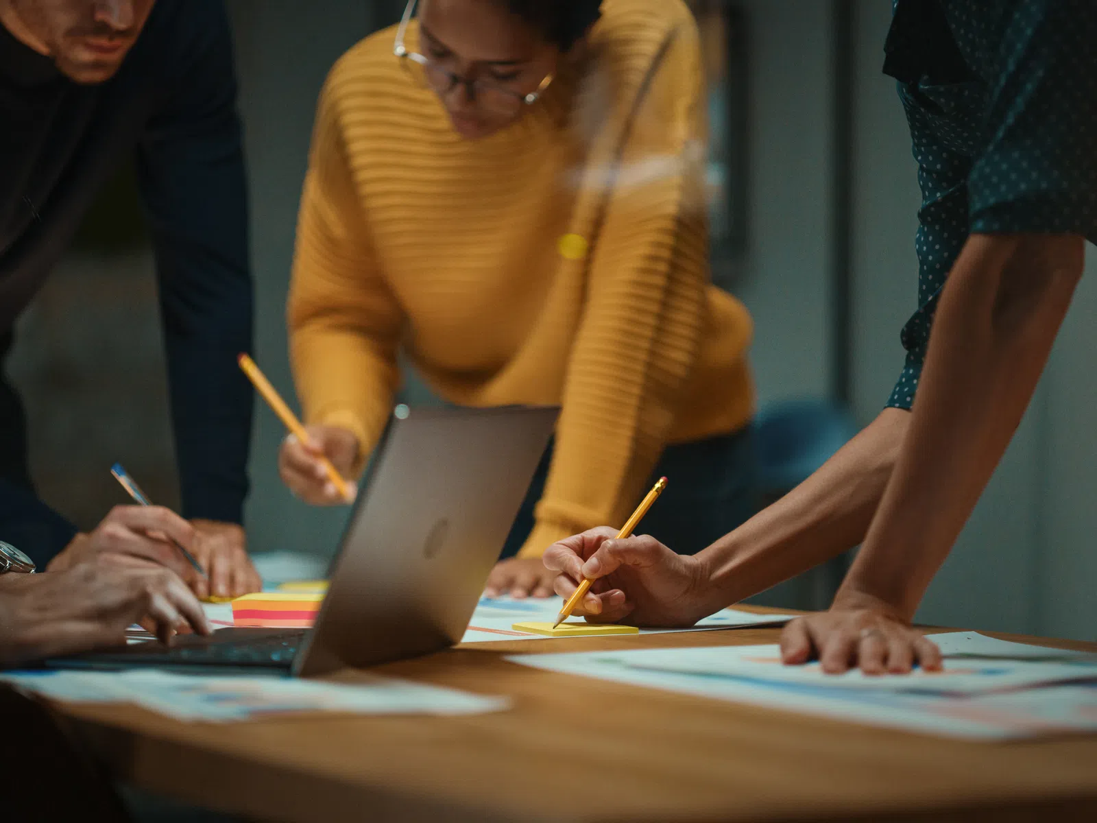 Team collaborating over documents and laptop, writing notes during a meeting in a modern office setting