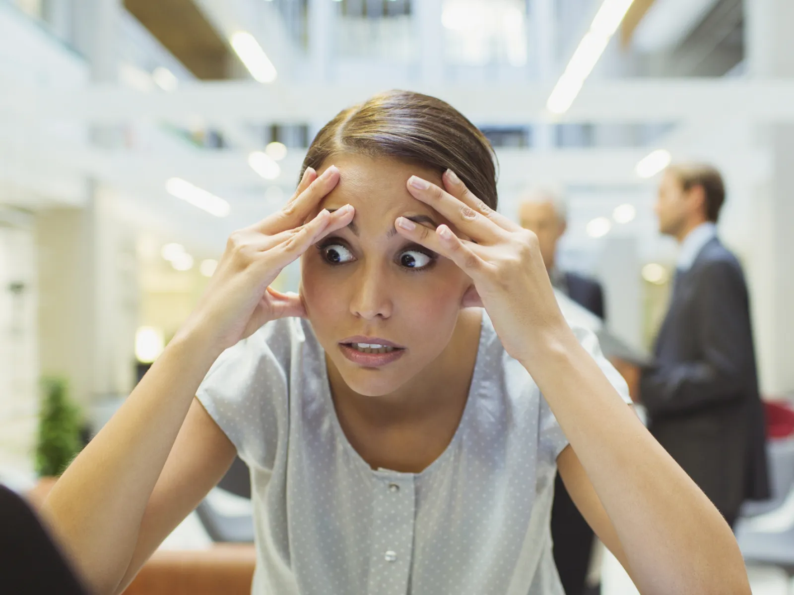 a woman with her hands on her head looking at a laptop