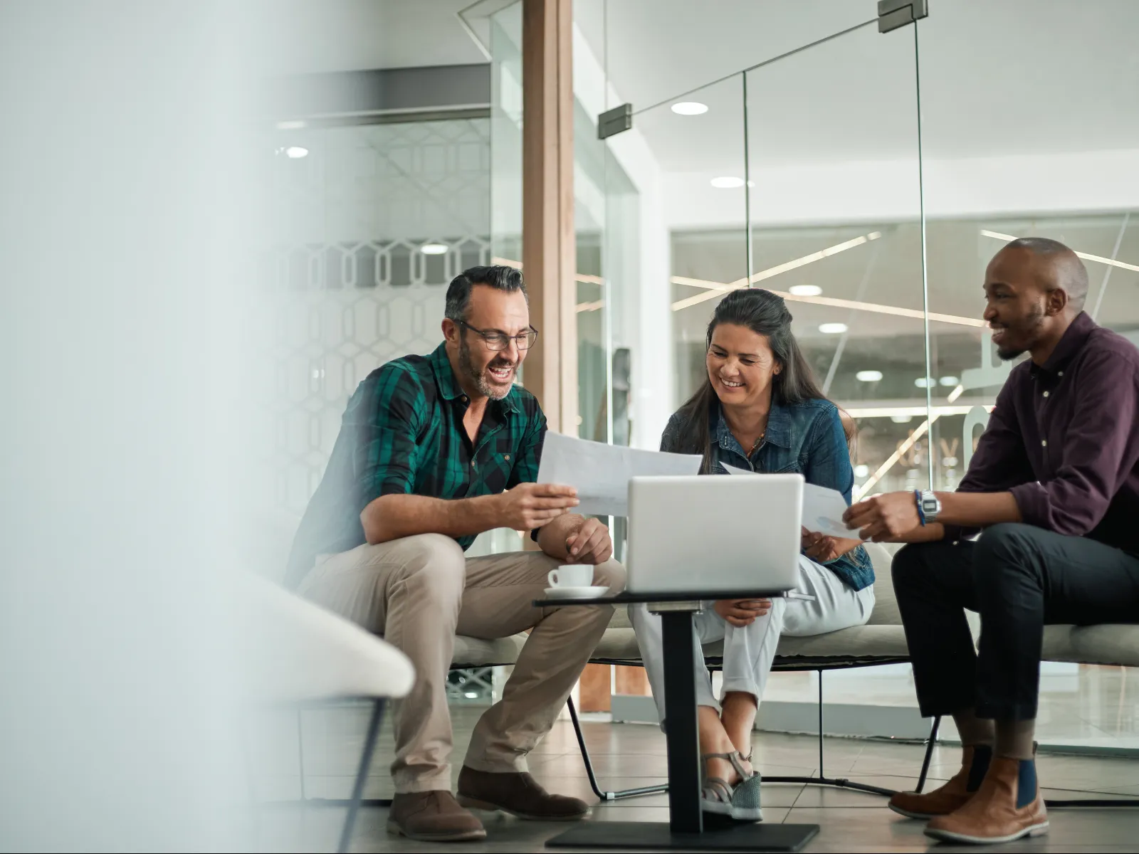 a group of people sitting on a couch looking at a laptop