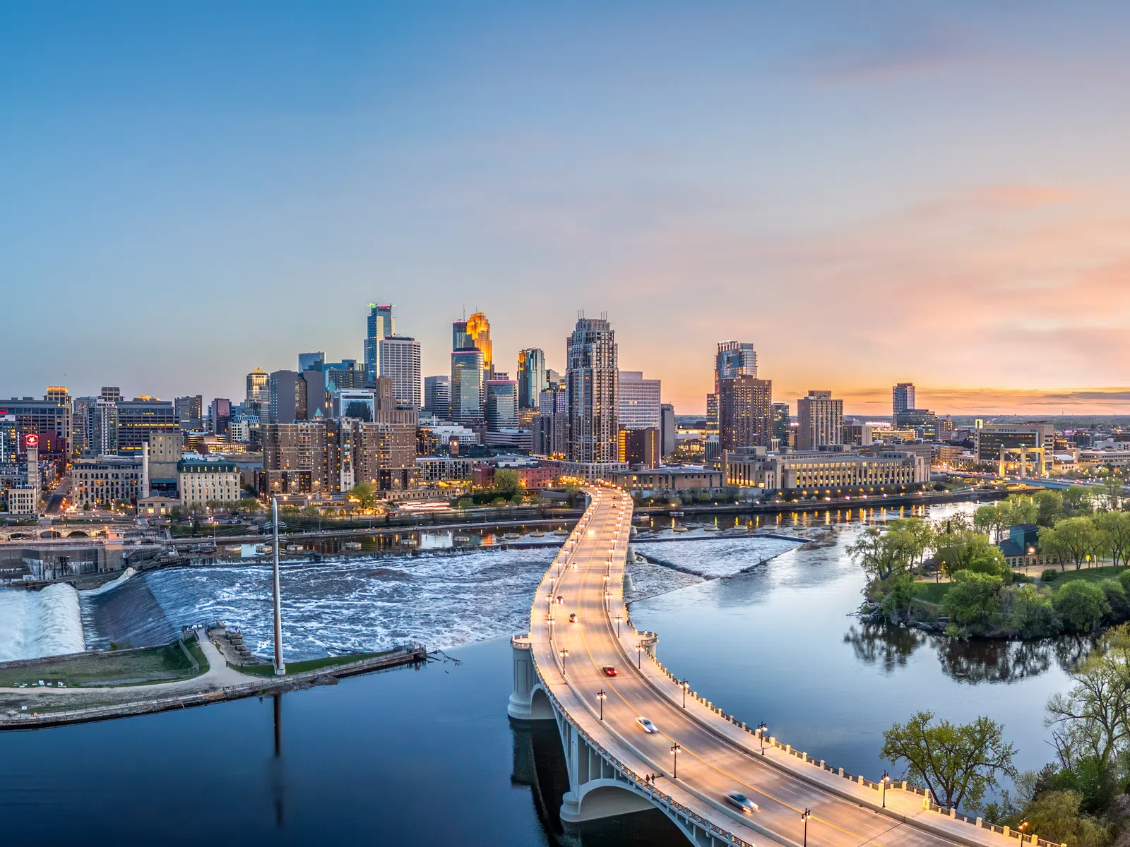 Aerial view of Minneapolis skyline at sunset with highway bridge over the Mississippi River and city buildings