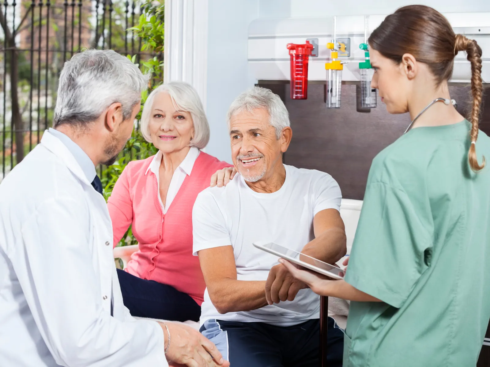 Senior couple consulting with doctor and nurse in a modern medical clinic setting indoors.
