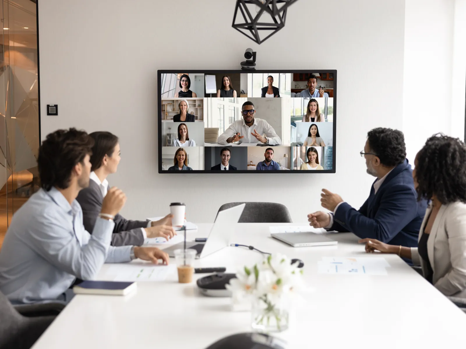 Business team in conference room having video meeting with remote colleagues on large screen