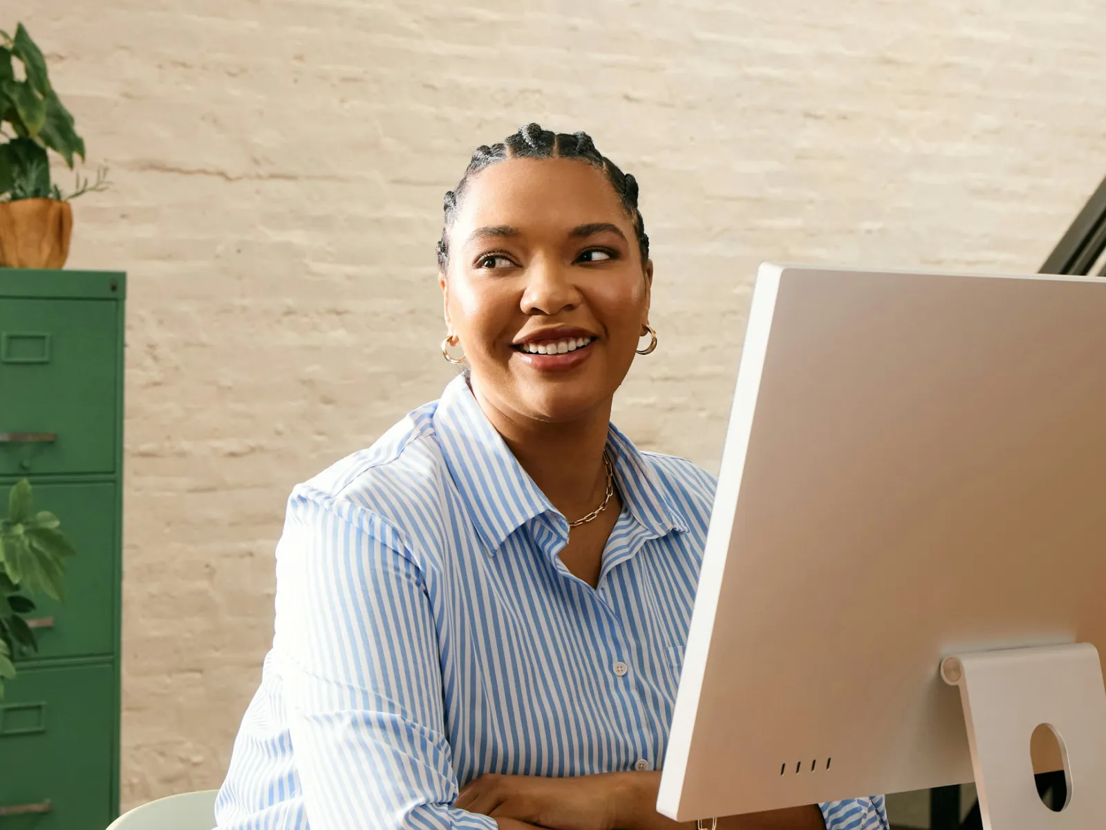 Two people having a casual outdoor meeting with laptops at a wooden table surrounded by greenery.