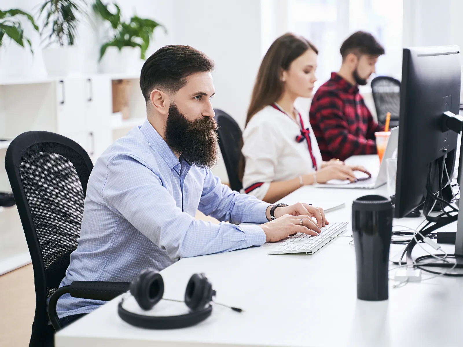 Three professionals working at desks in a modern office environment.