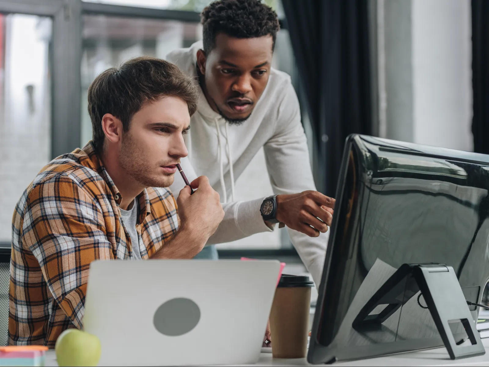 Two professionals collaborating at a desk, analyzing data on a computer screen.