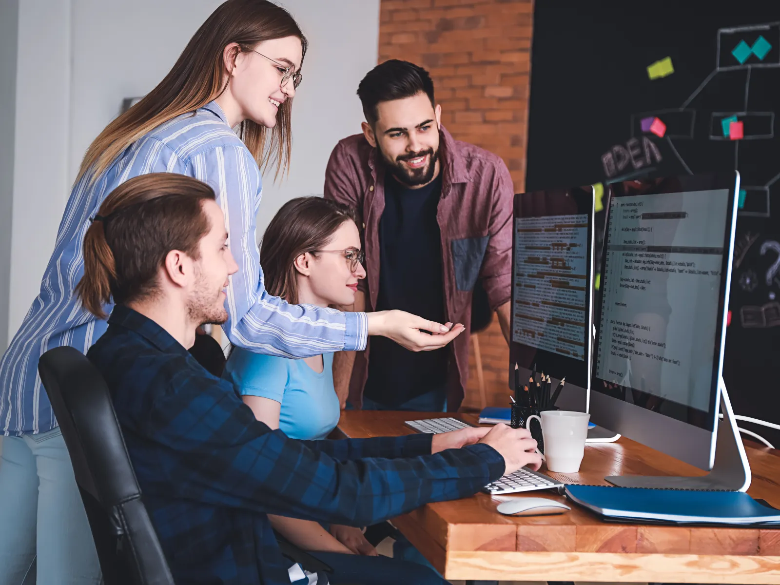 A team collaborating around computers in a modern office environment, focused on their work.
