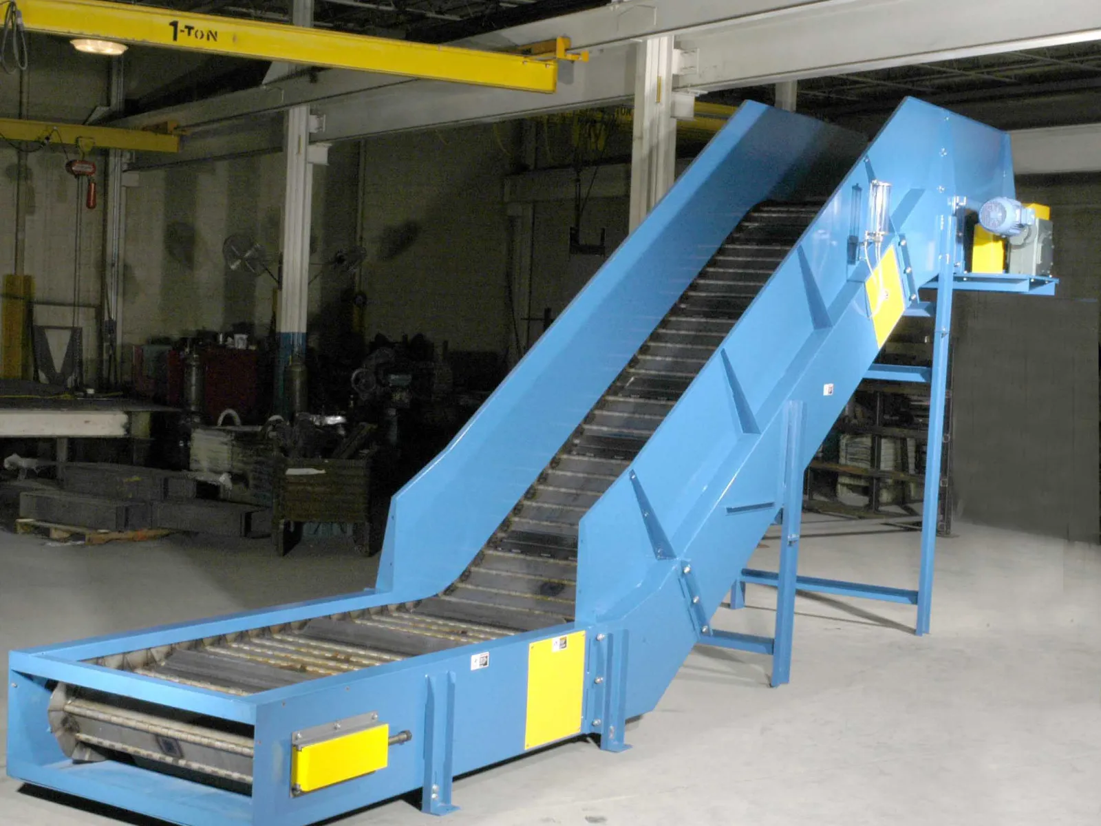 Large red industrial conveyor system with yellow safety panels inside a spacious warehouse facility.