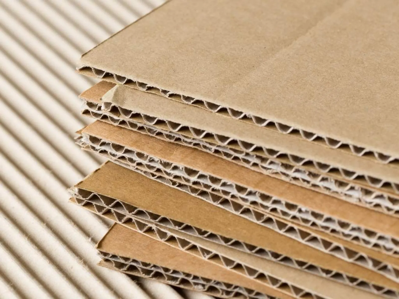 Close-up of stacked corrugated cardboard sheets showing the texture and layers of brown packaging material.