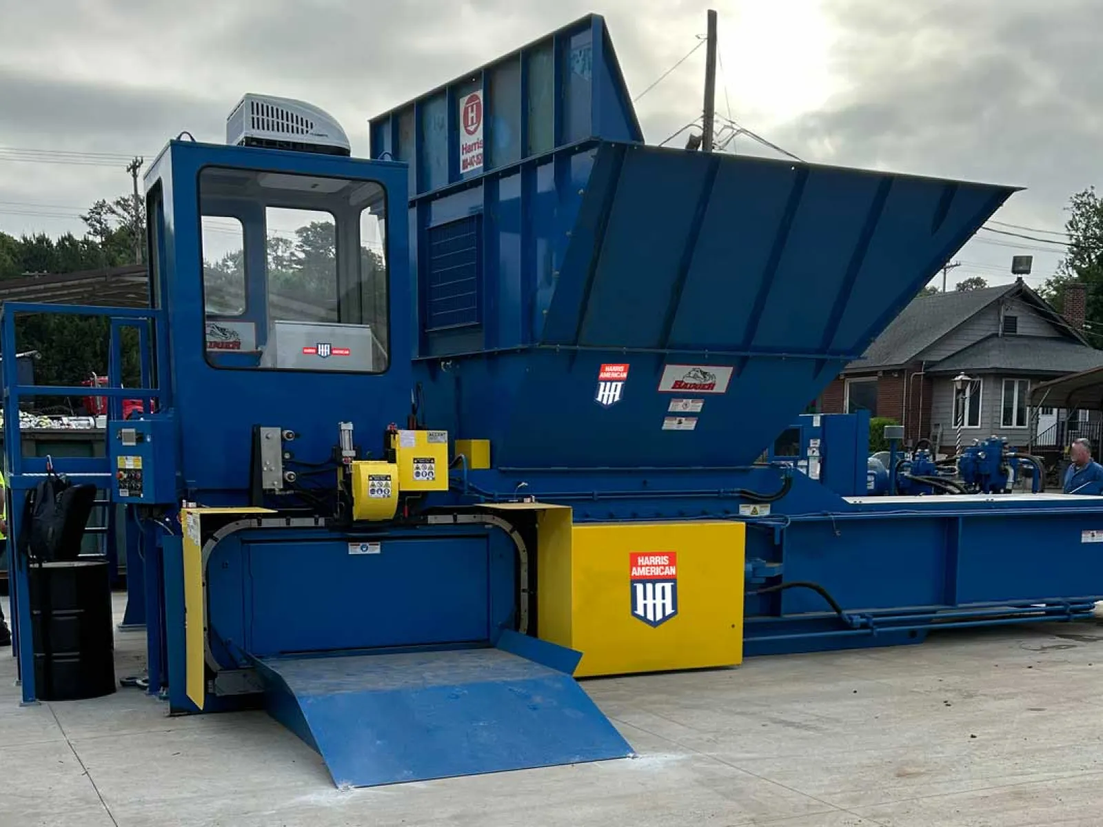 Industrial green baler machine compressing cardboard bales inside a warehouse.