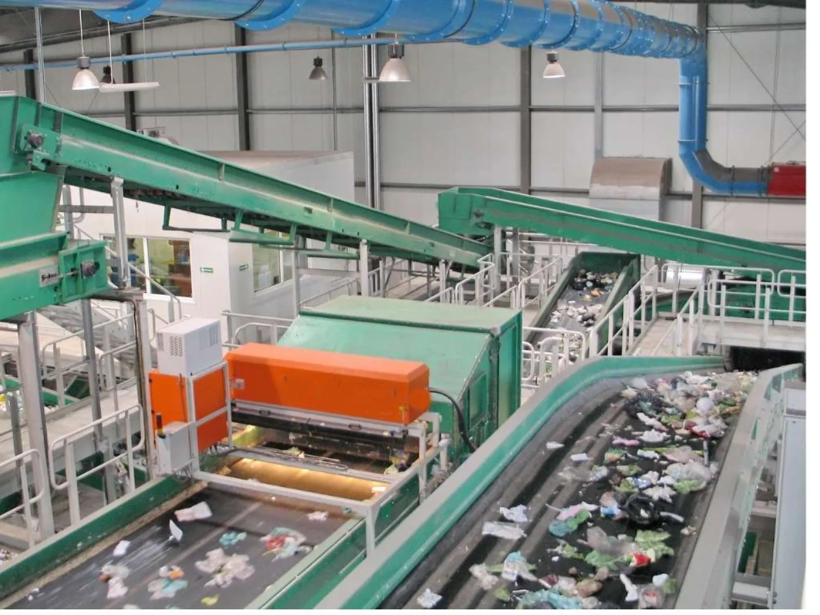 Interior view of a recycling facility with conveyor belts sorting plastic waste and debris inside an industrial building