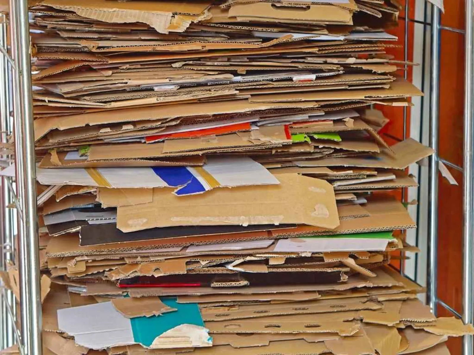 Stack of flattened cardboard boxes neatly piled on metal shelving for recycling or storage.