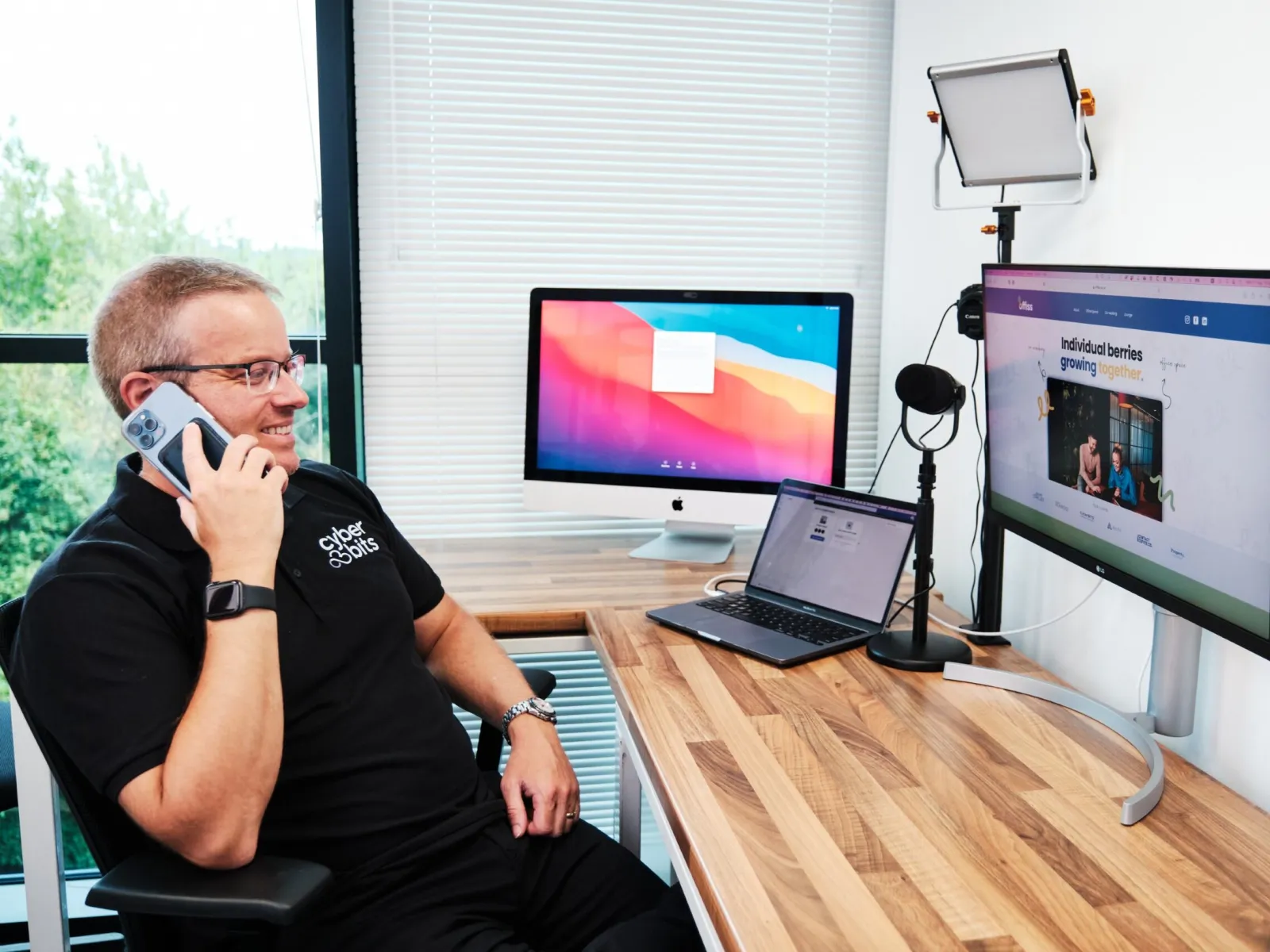 a man sitting at a desk with a laptop and a computer