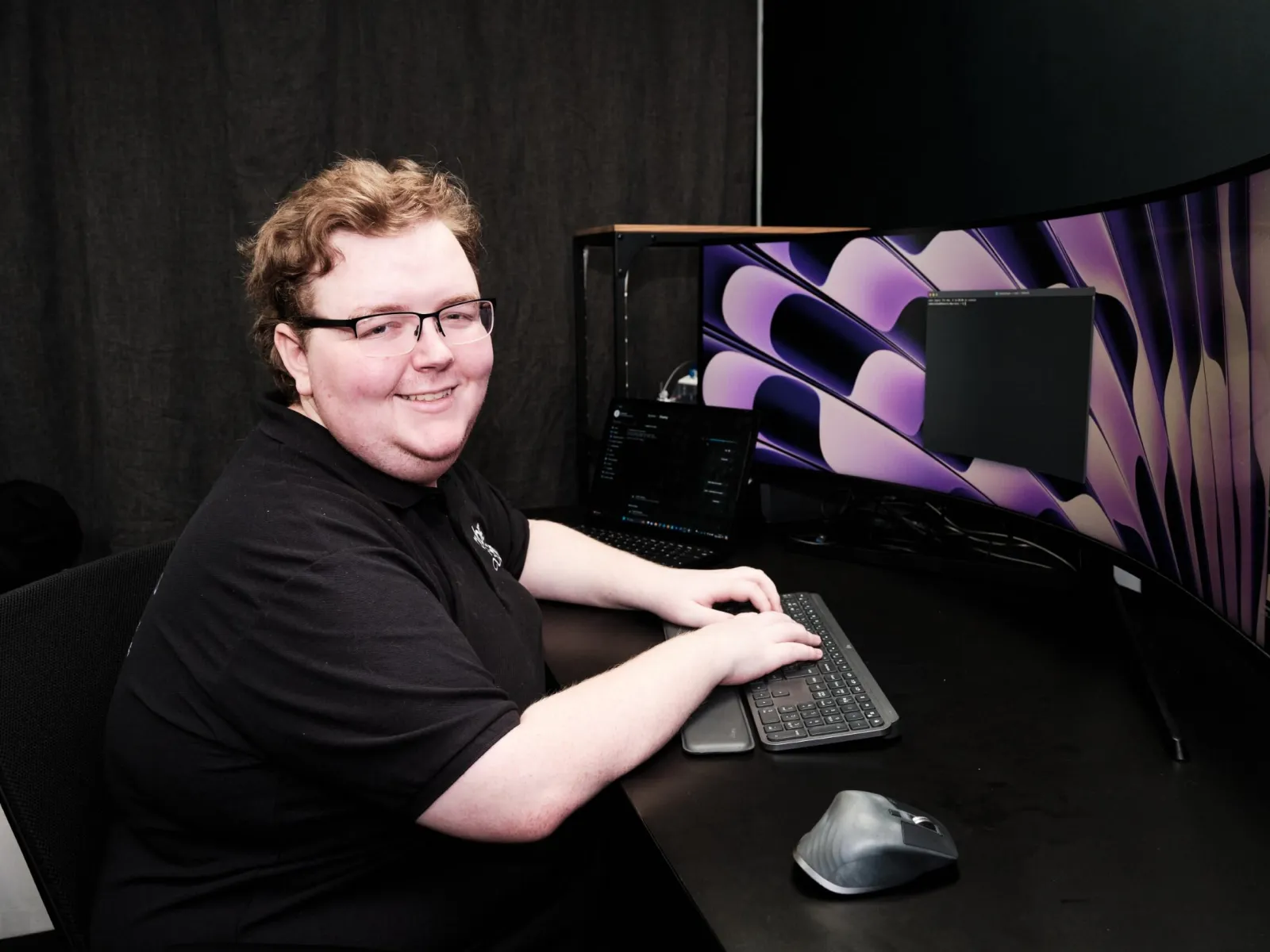 a person sitting at a desk with a computer and a keyboard