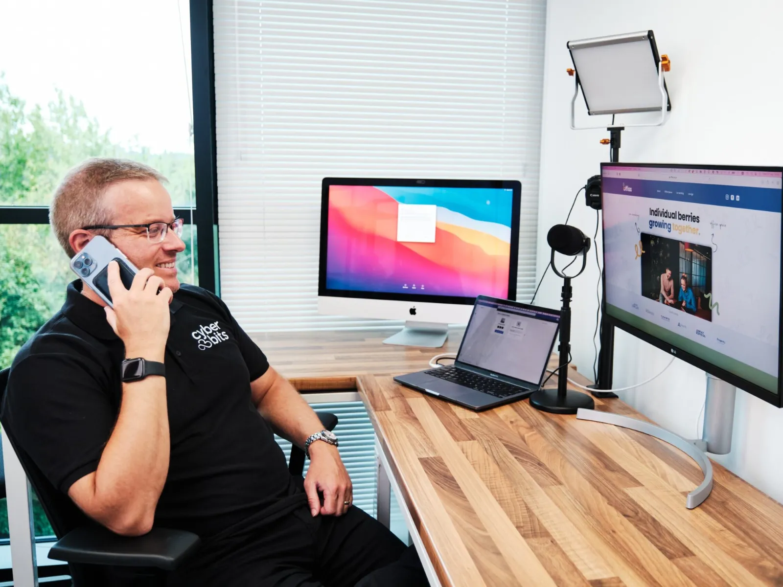 a man sitting at a desk with a laptop and a computer