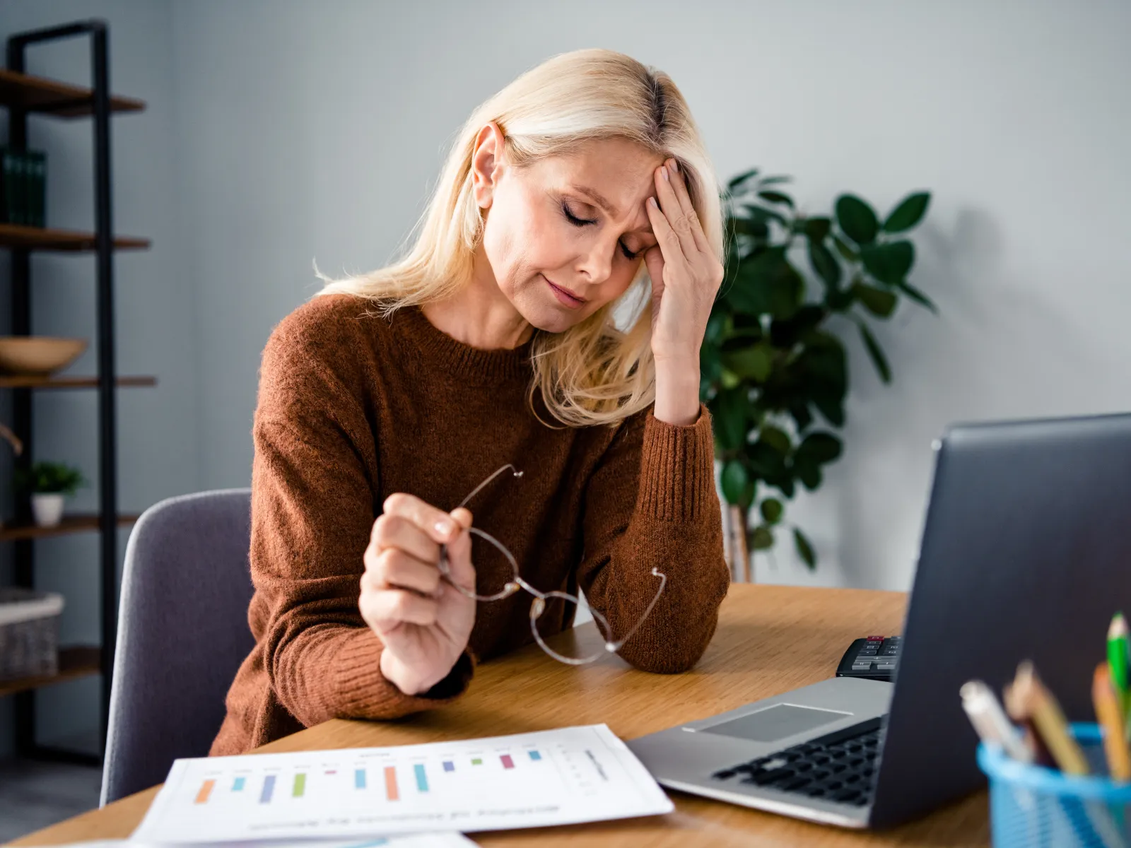 a woman sitting at a desk with her hands on her face