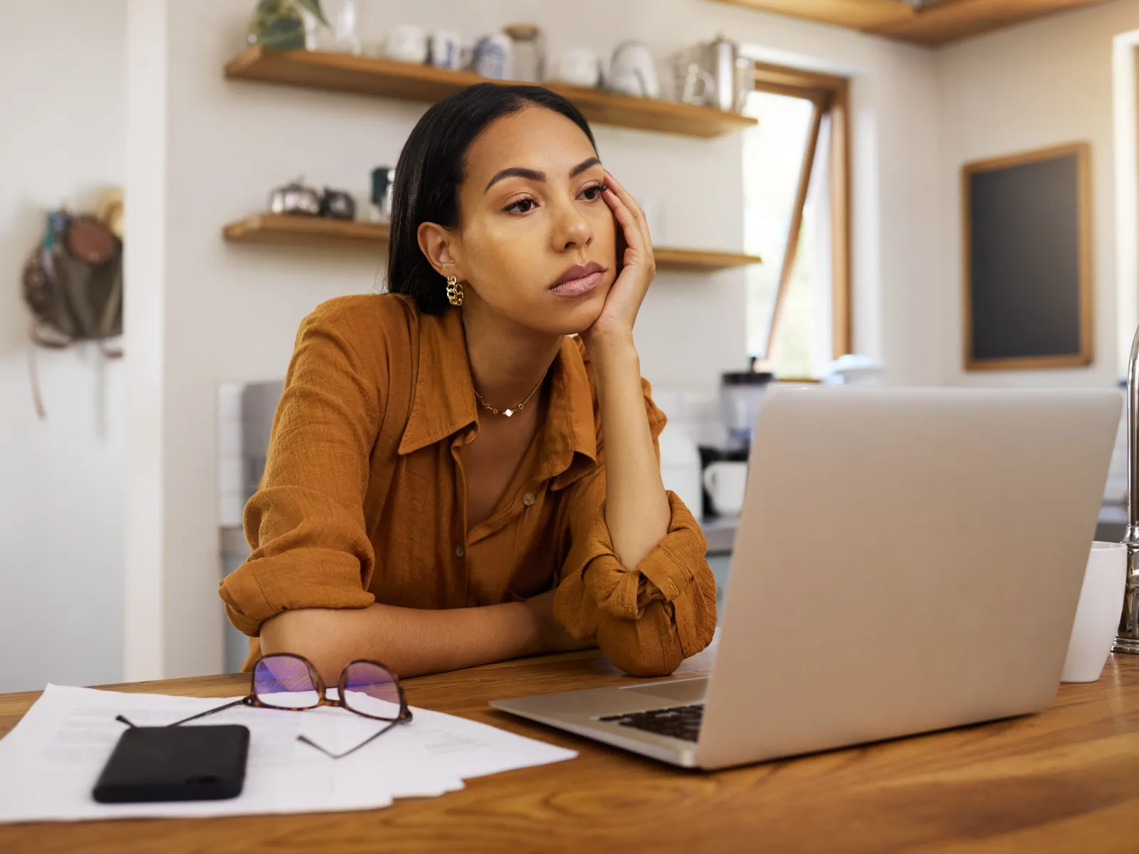 a woman sitting at a table with a laptop and papers