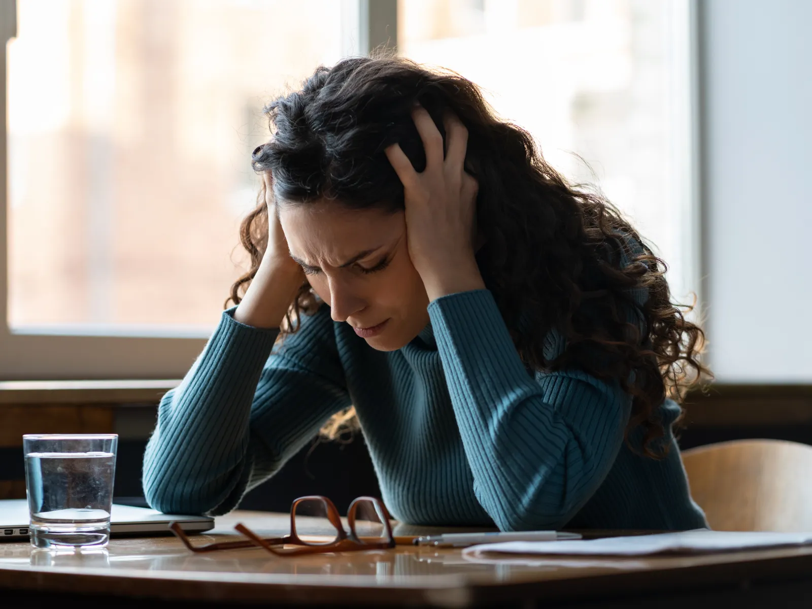 a woman with her head in her hands looking at a book