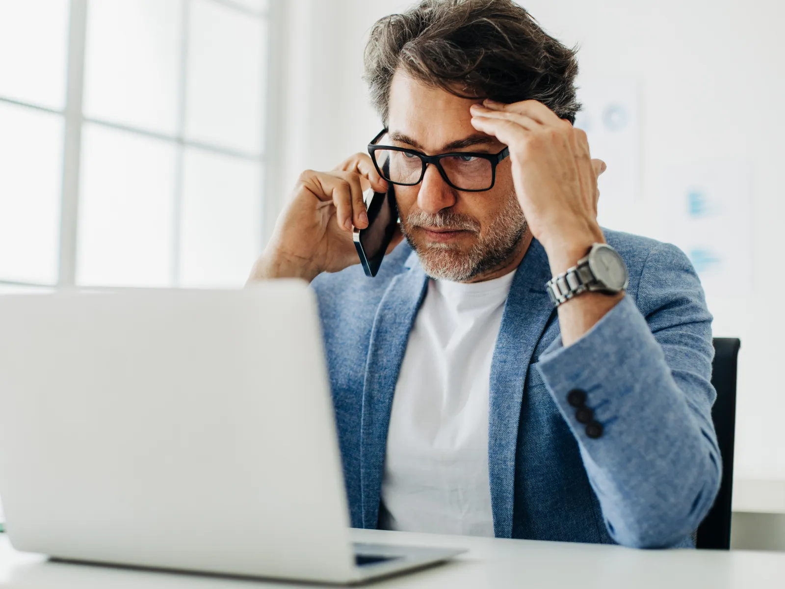 a man with his hands on his face looking at a laptop
