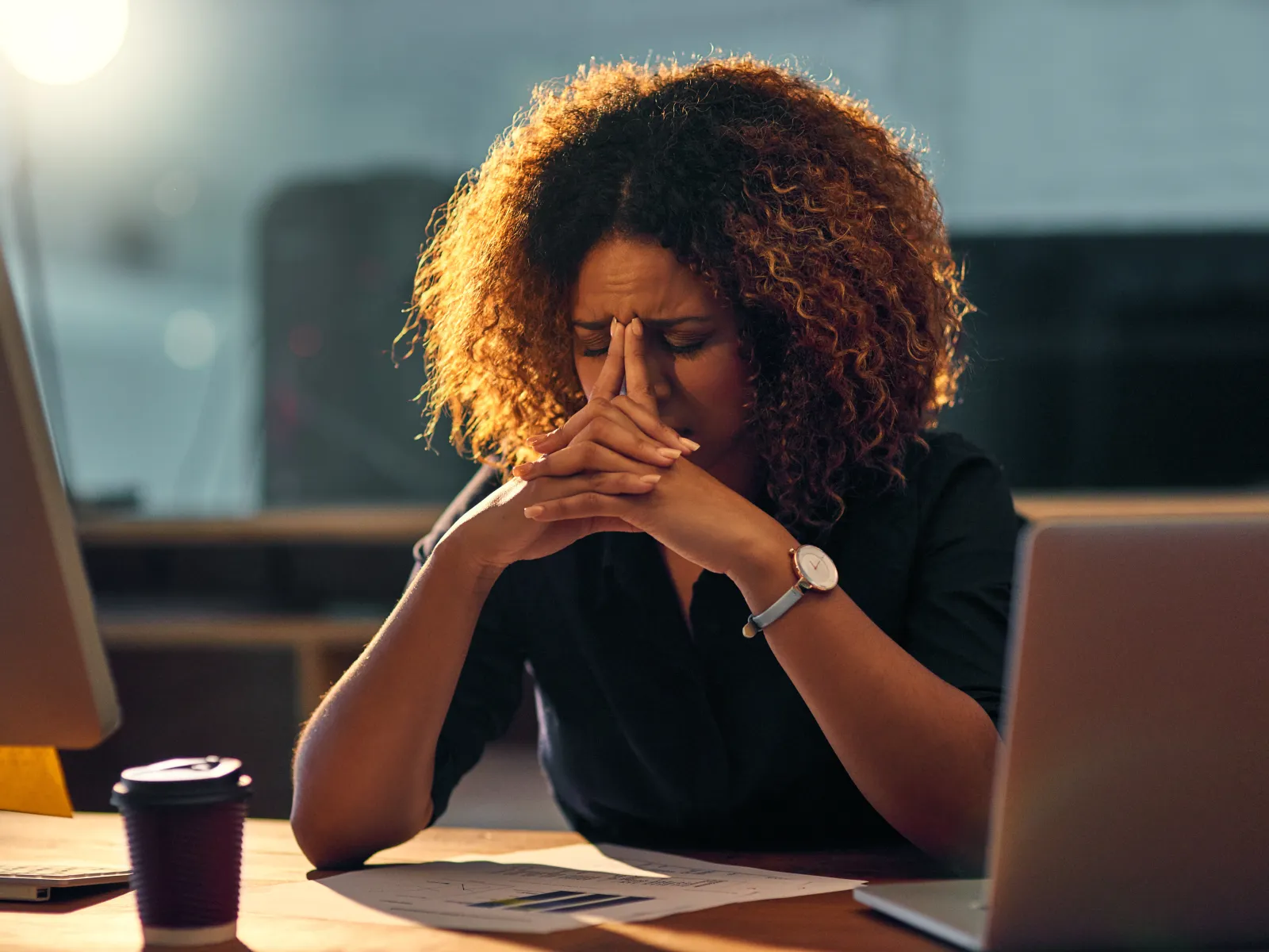 a person with curly hair sitting at a desk with a laptop