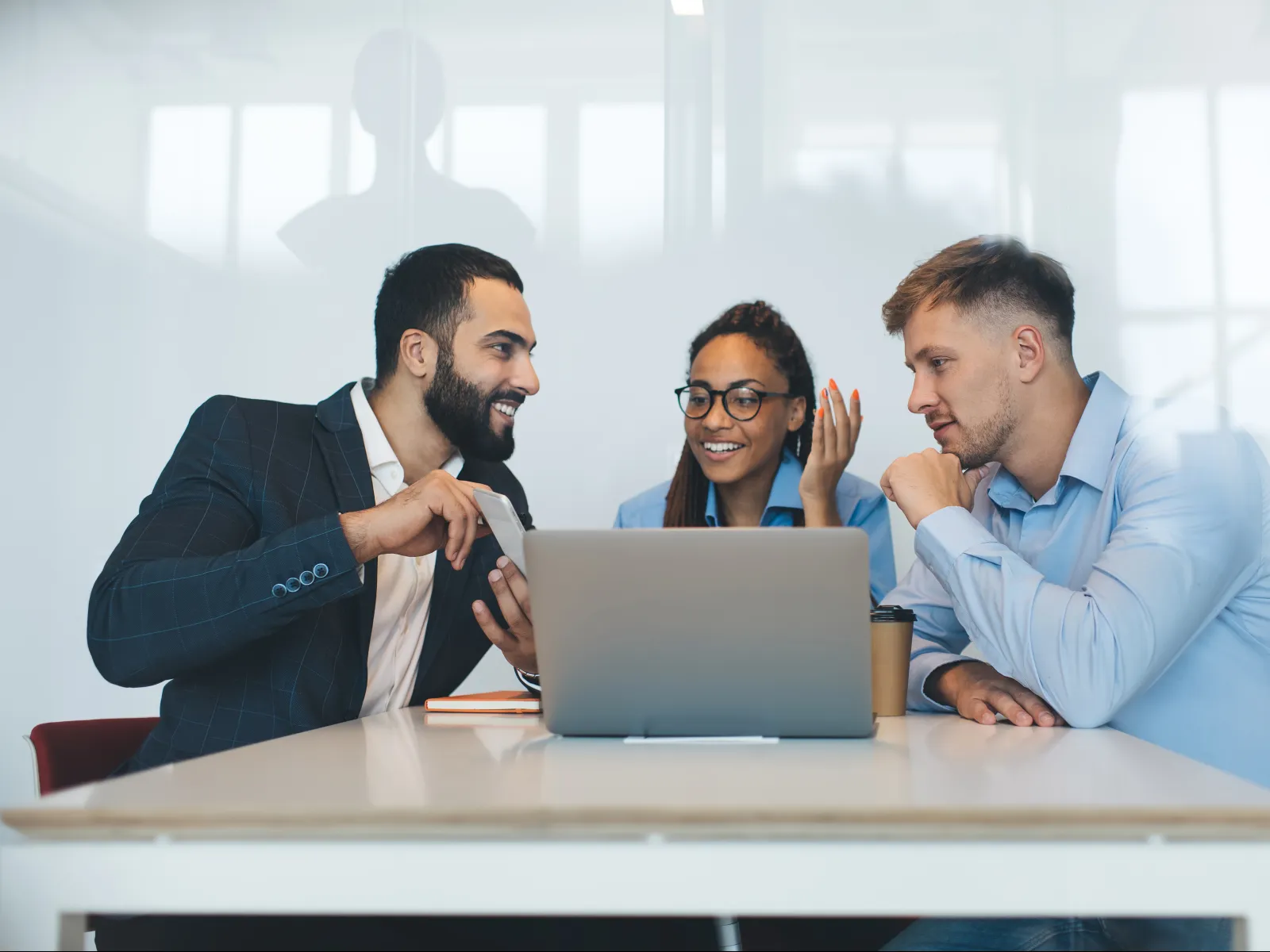 a group of men sitting at a table with a laptop