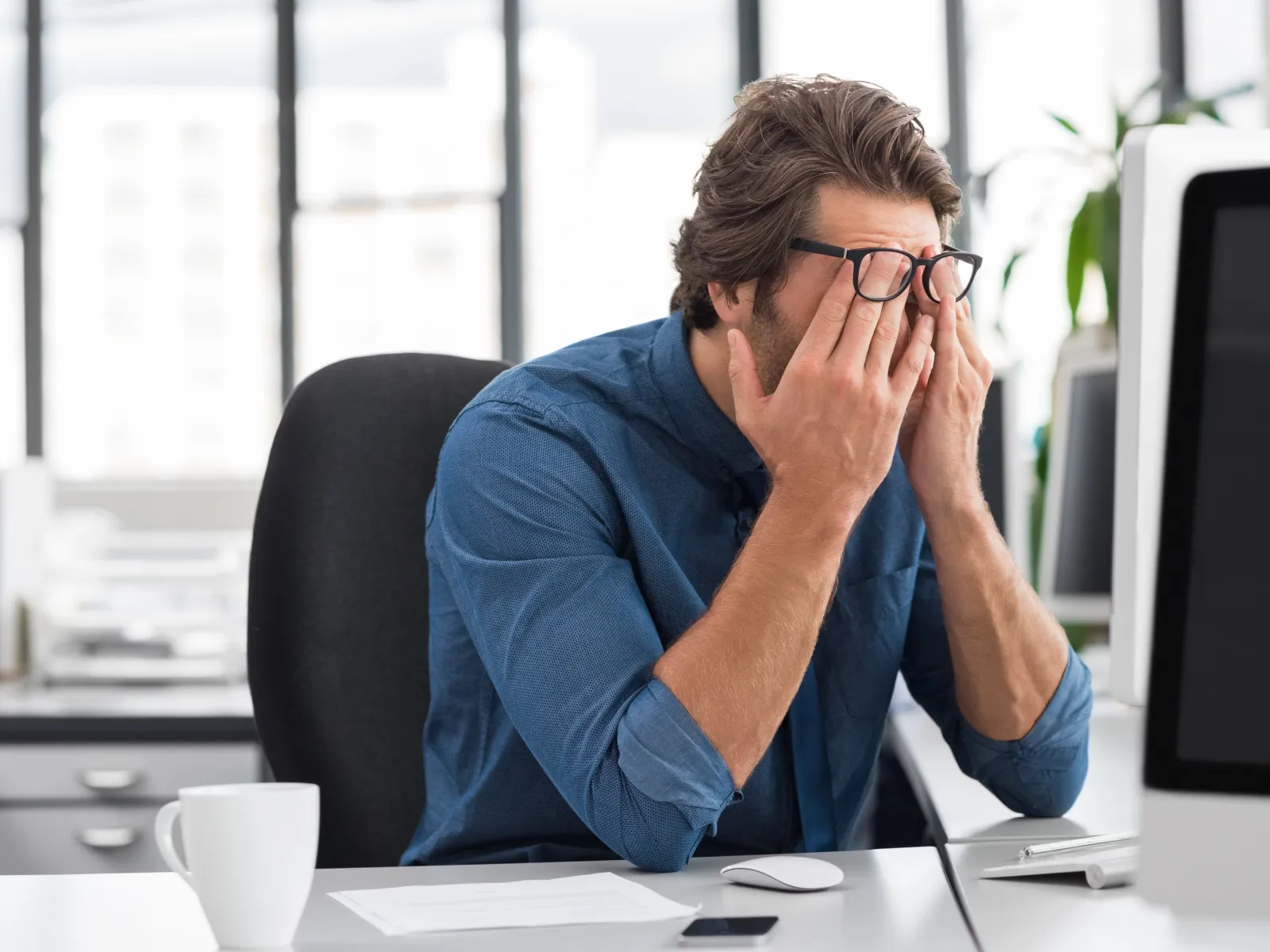 a person sitting at a desk with the hands to the face