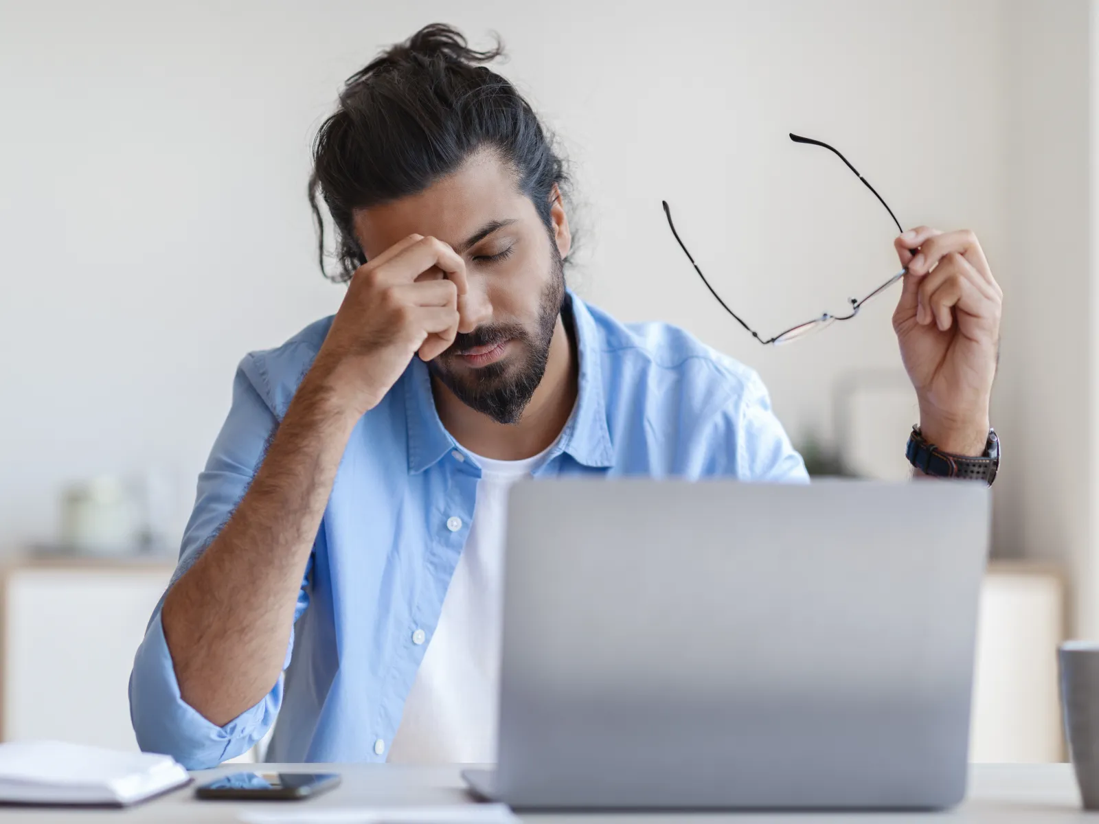 a person with the hands on the face looking at a laptop