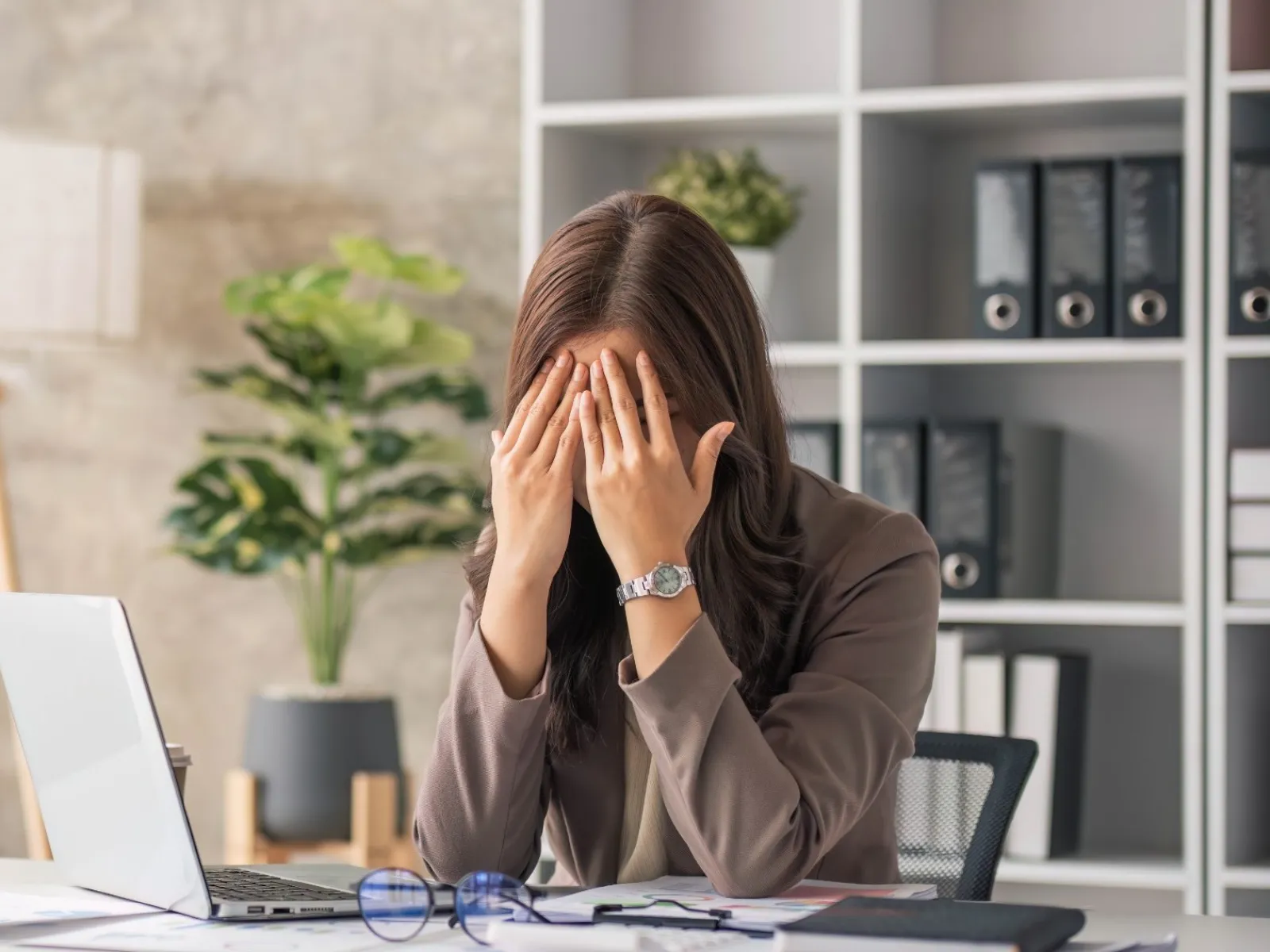 a woman sitting at a desk with her hand on her face