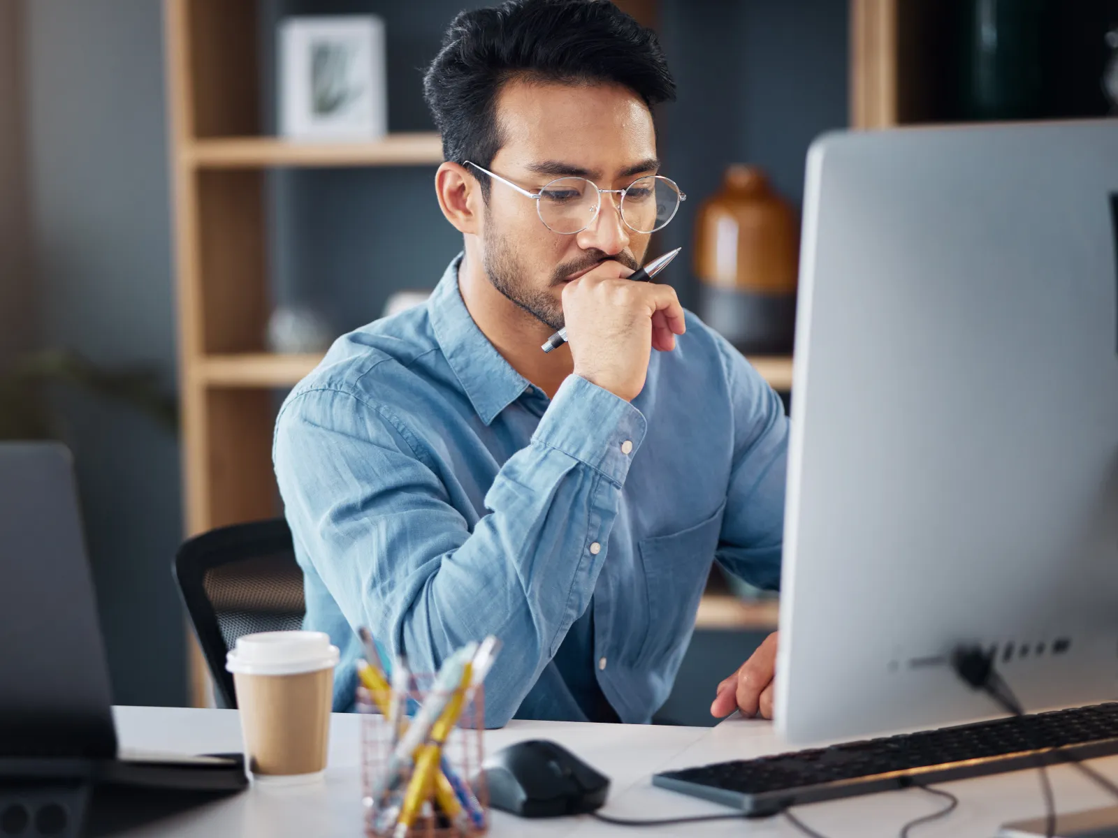a man sitting at a desk with a laptop and a cup
