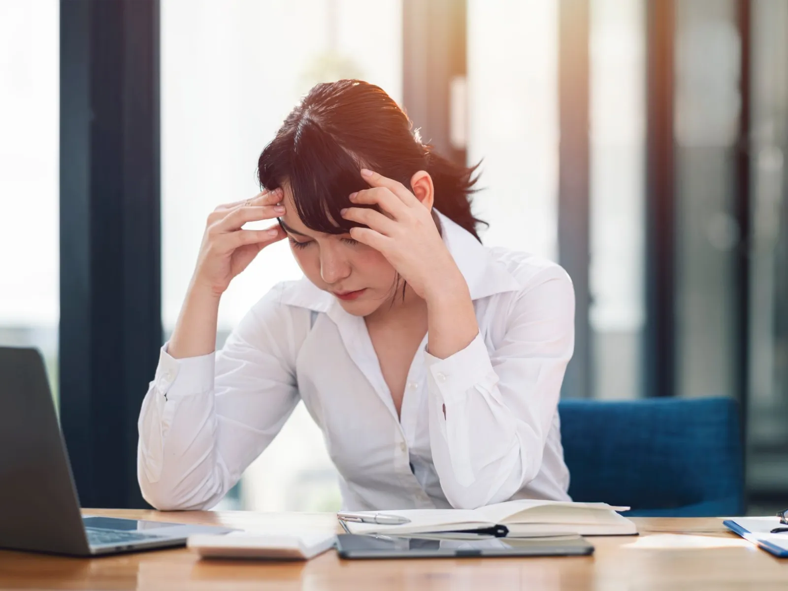 a woman sitting at a desk with her head in her hands