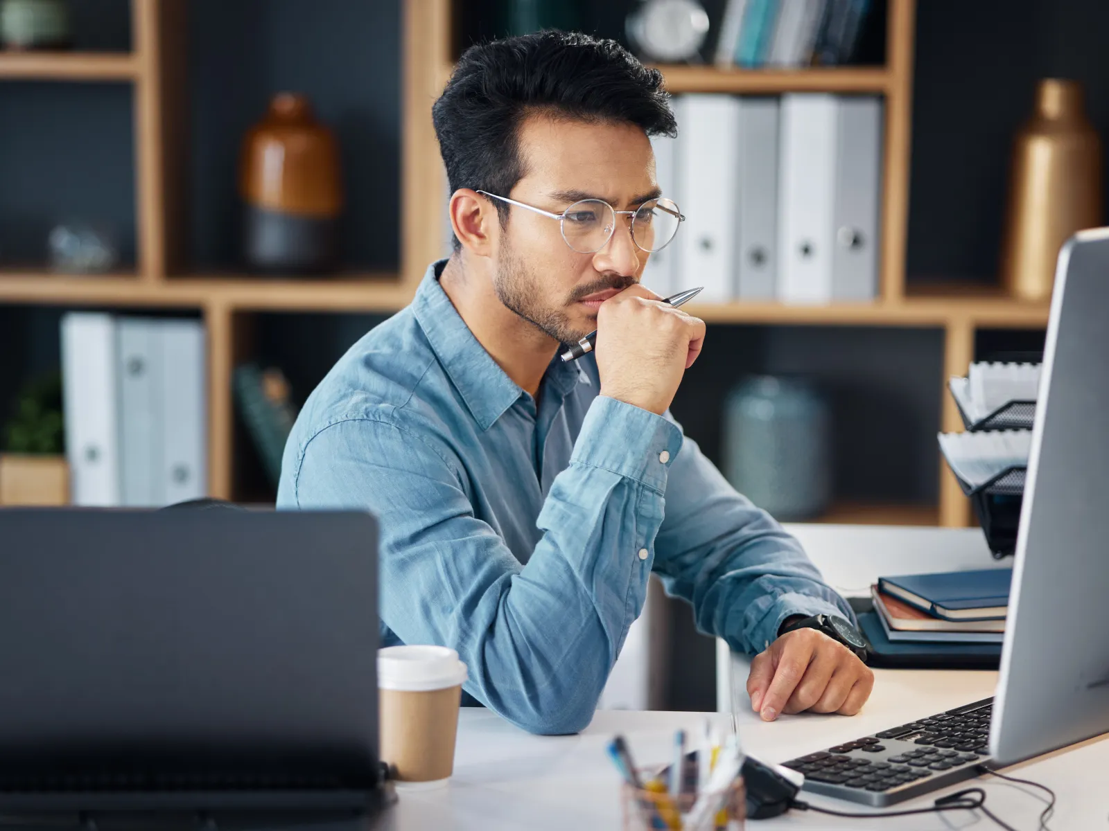 a man sitting at a desk with a laptop and a cup