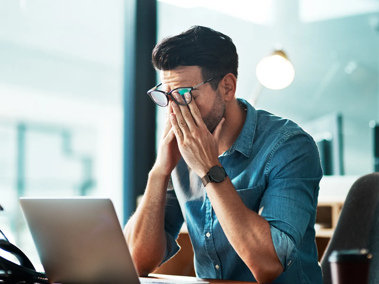 a man with his hand on his face looking at a laptop