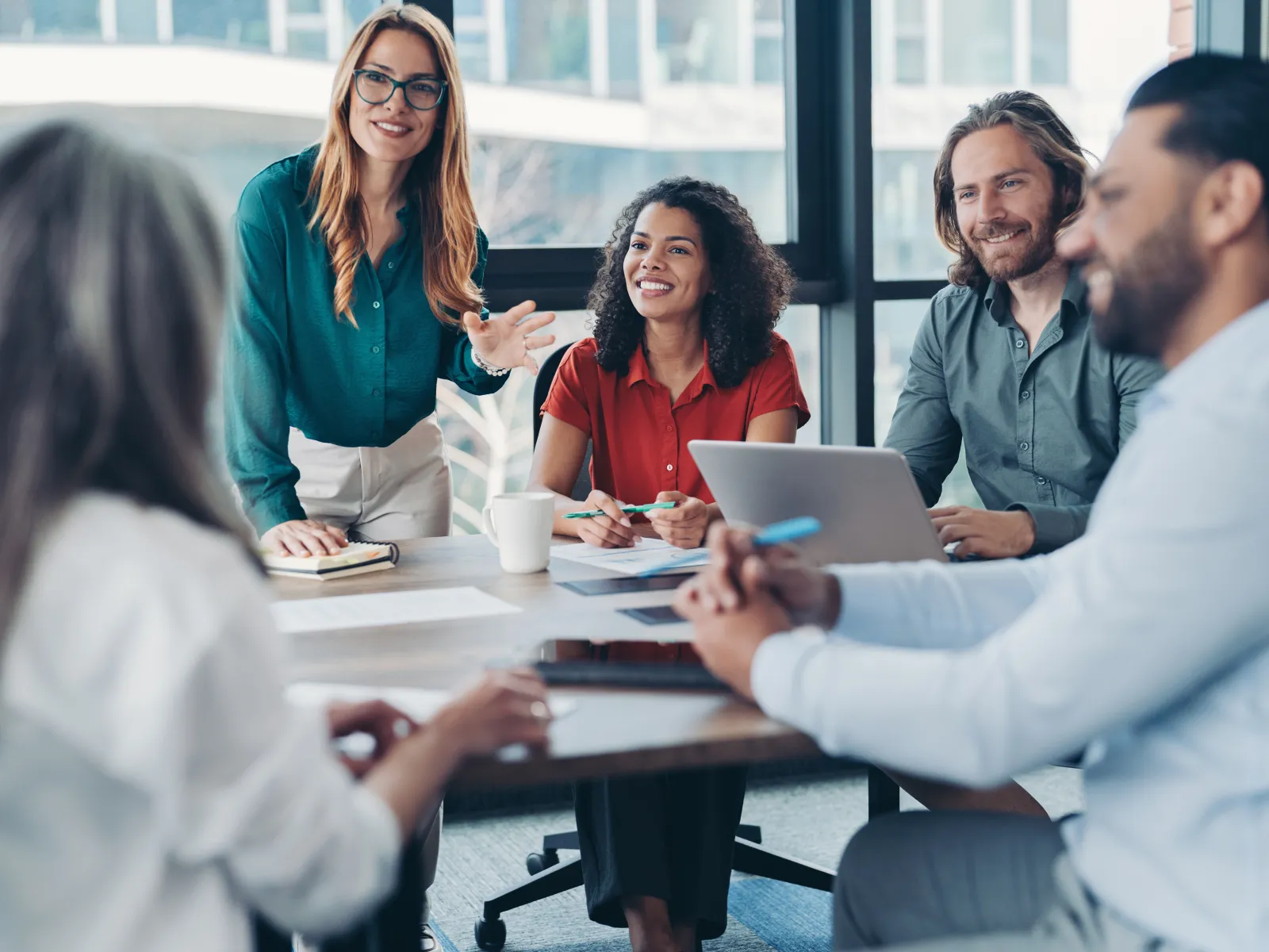 Diverse business team brainstorming around a table with laptops and papers in a modern office.