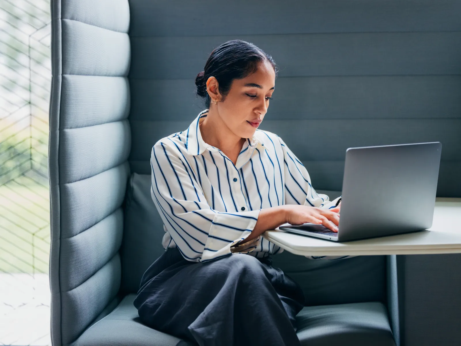 Three diverse business colleagues collaborating on a project using a laptop in a modern office.