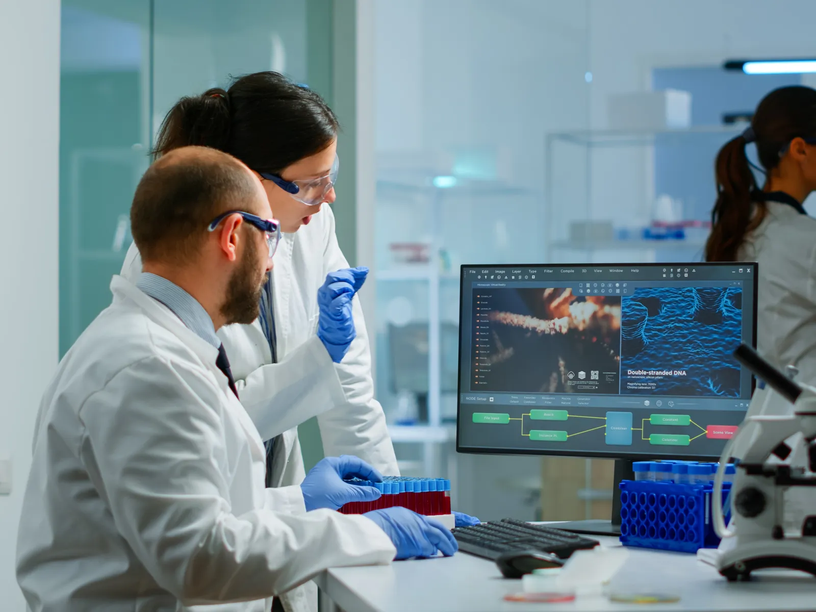 Scientists in lab coats analyze data on computer screens in a modern laboratory setting with microscope.