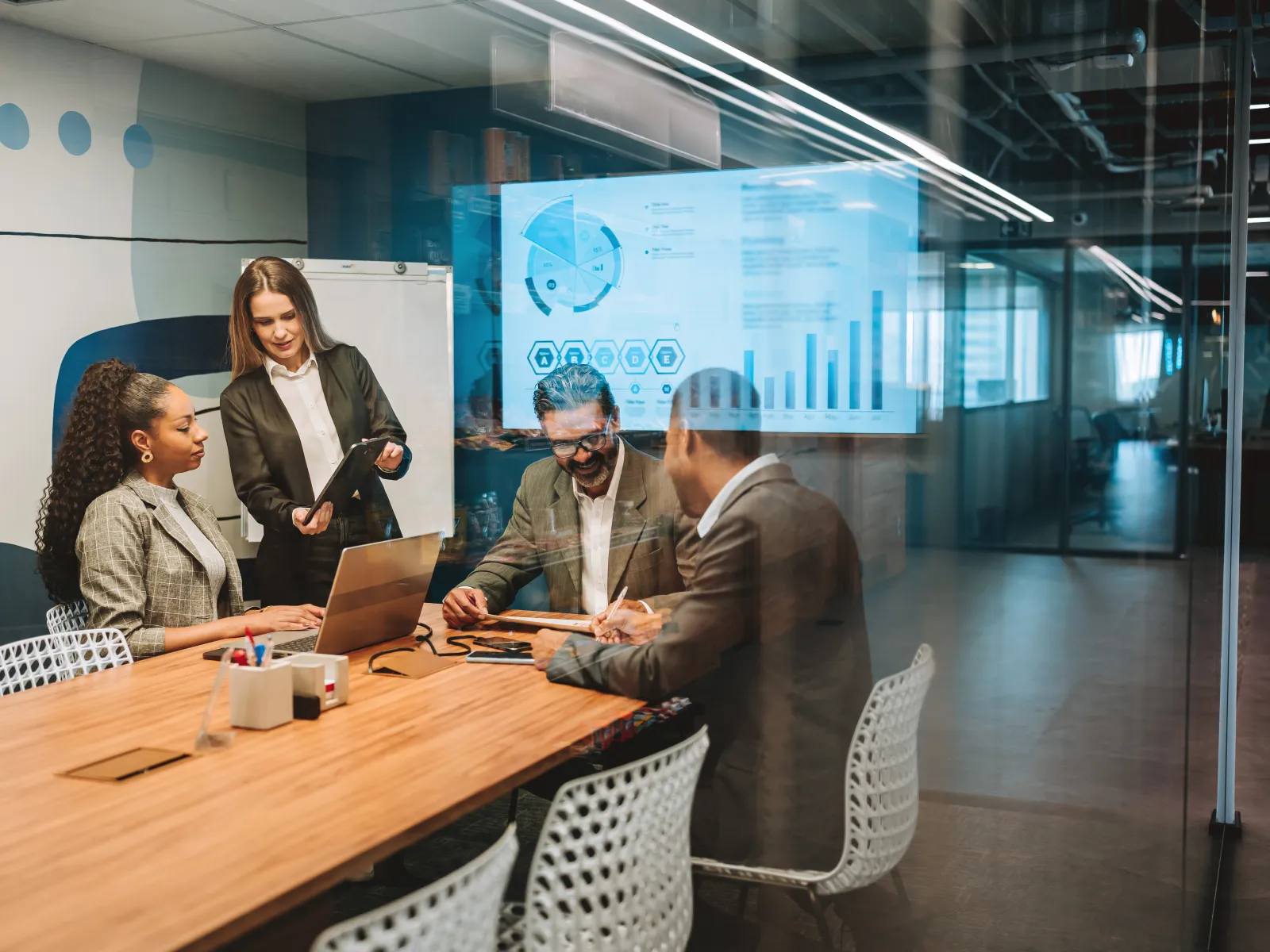 Two professionals collaborating on a project in a modern office, reviewing information on laptop and tablet.