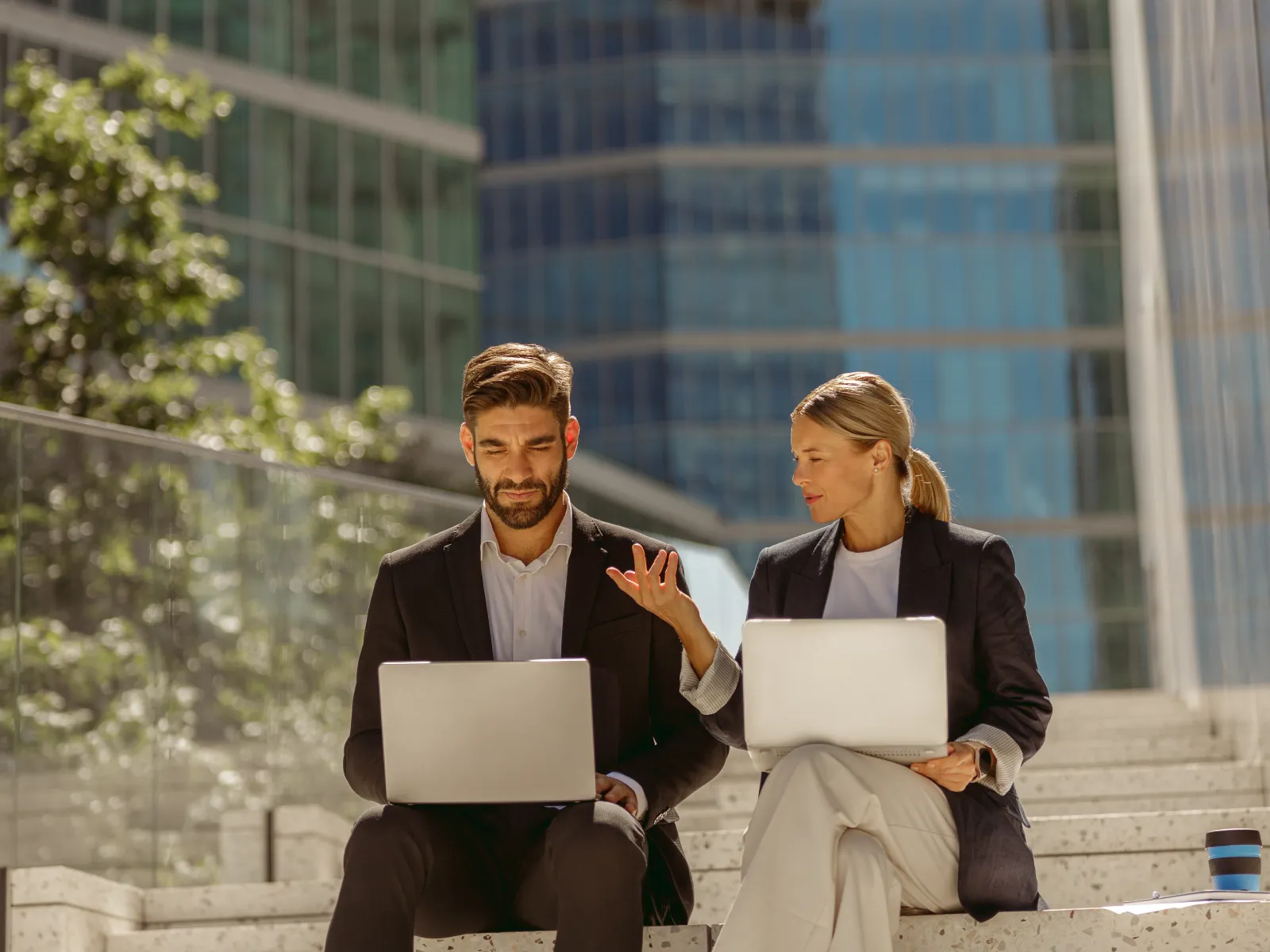 a man and a woman sitting on a ledge with a laptop