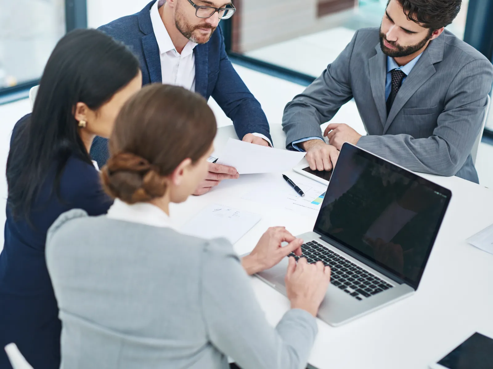 a group of people sitting around a table looking at a laptop