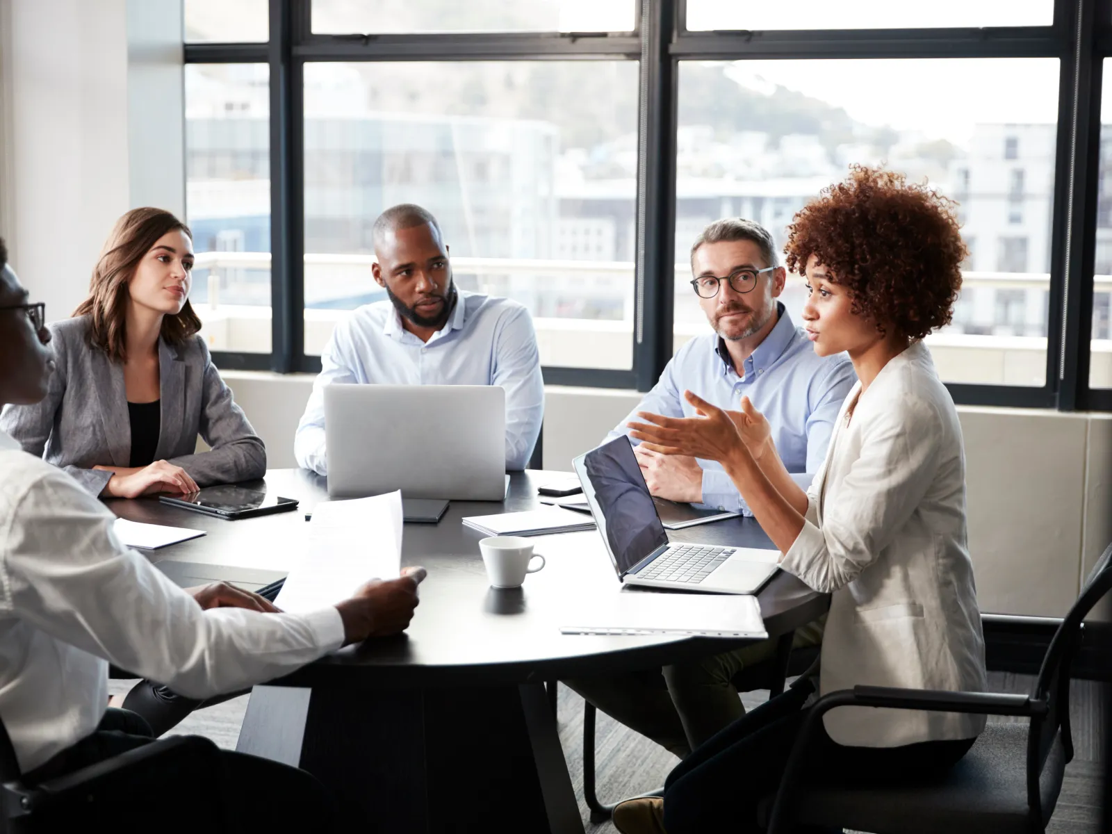 a group of people sitting around a table with laptops