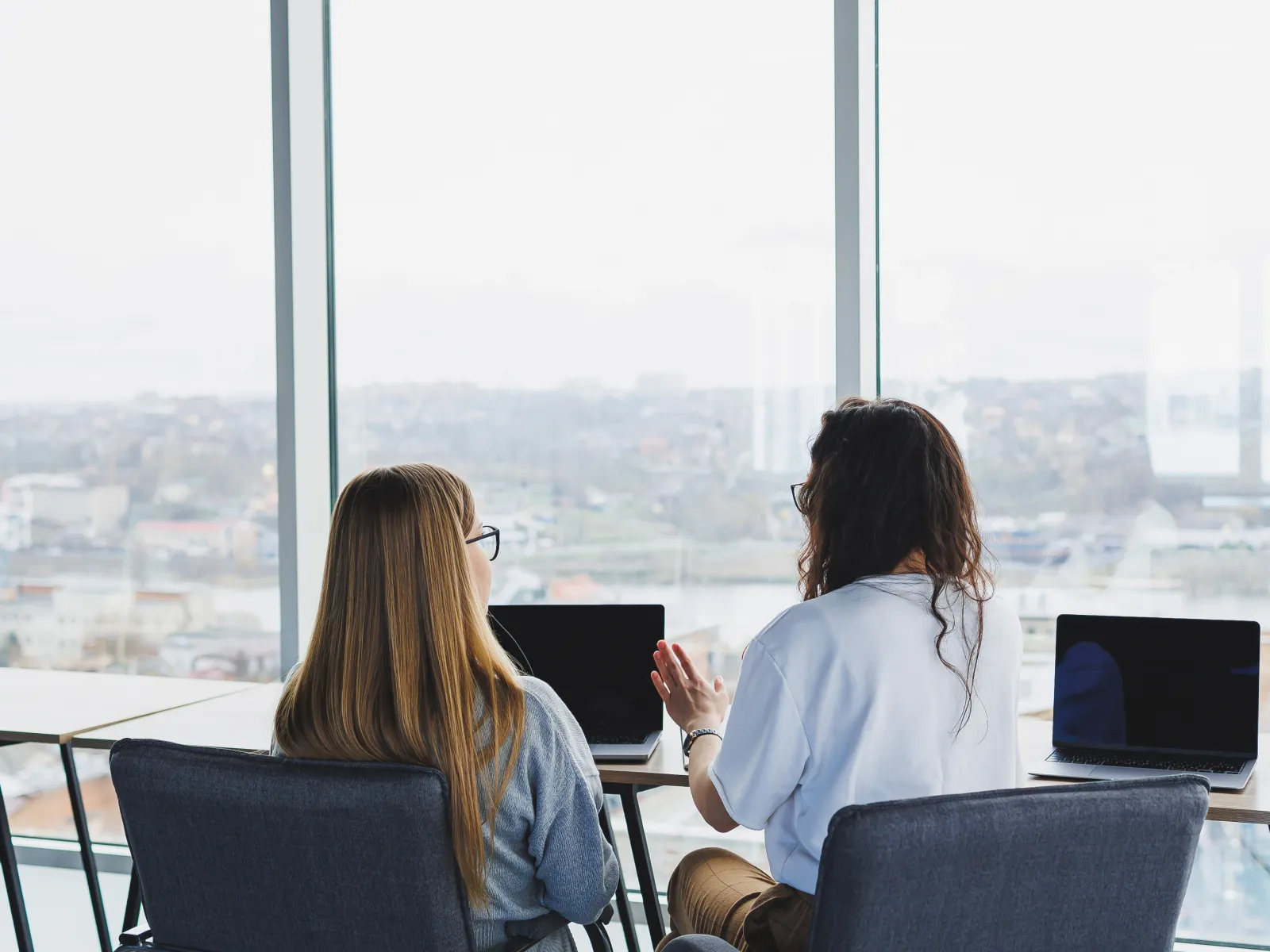 a couple of women sitting at a table looking out a window