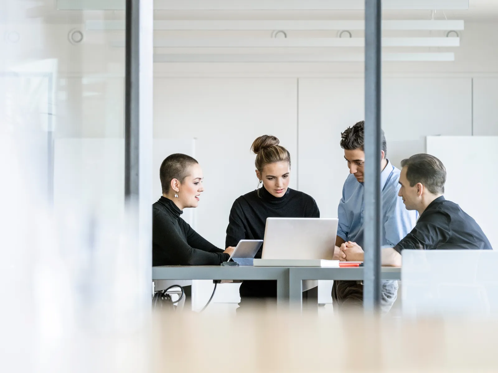 a group of people sitting at a table looking at a laptop